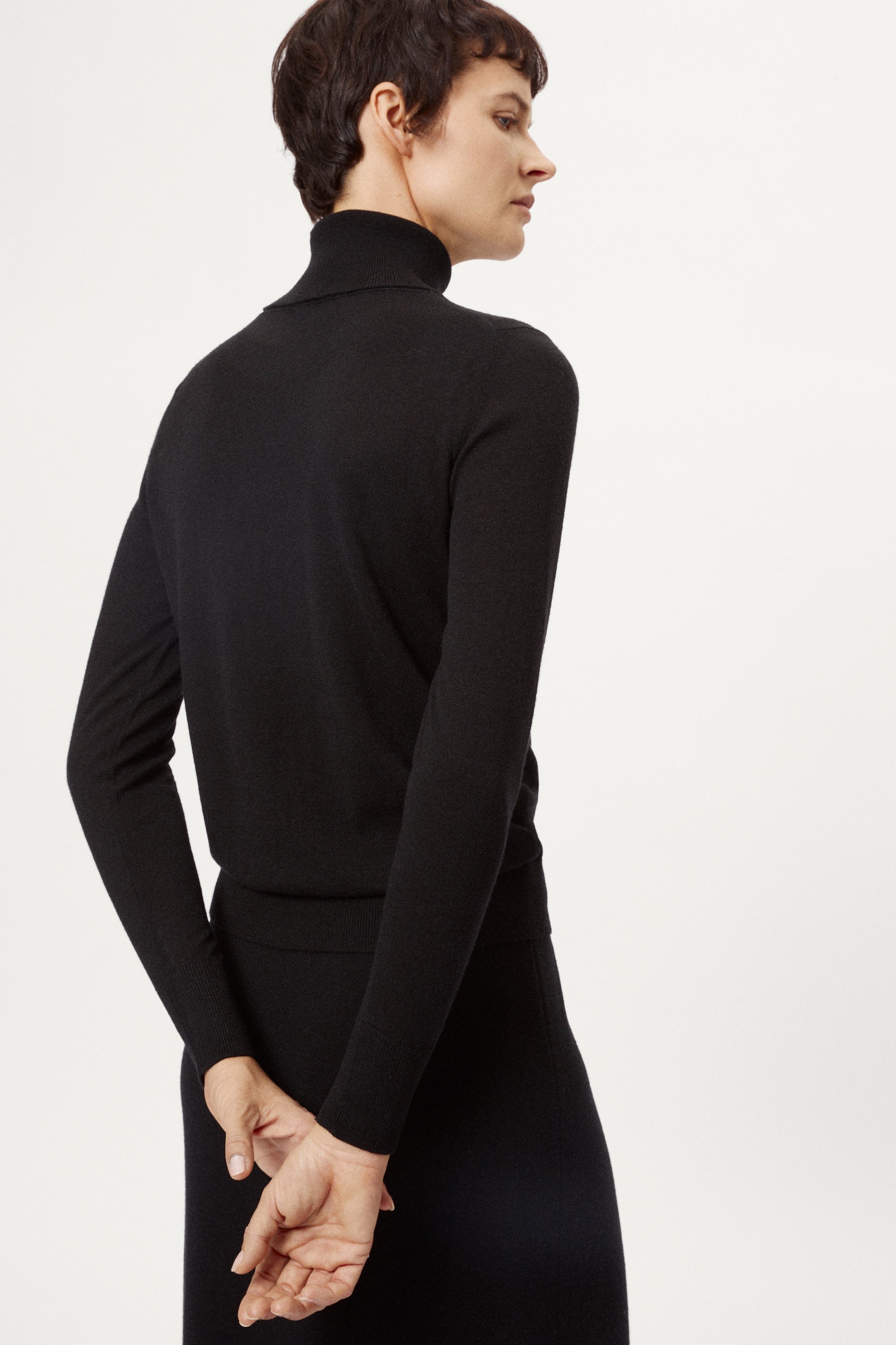 Person wearing a black turtleneck sweater on a white background