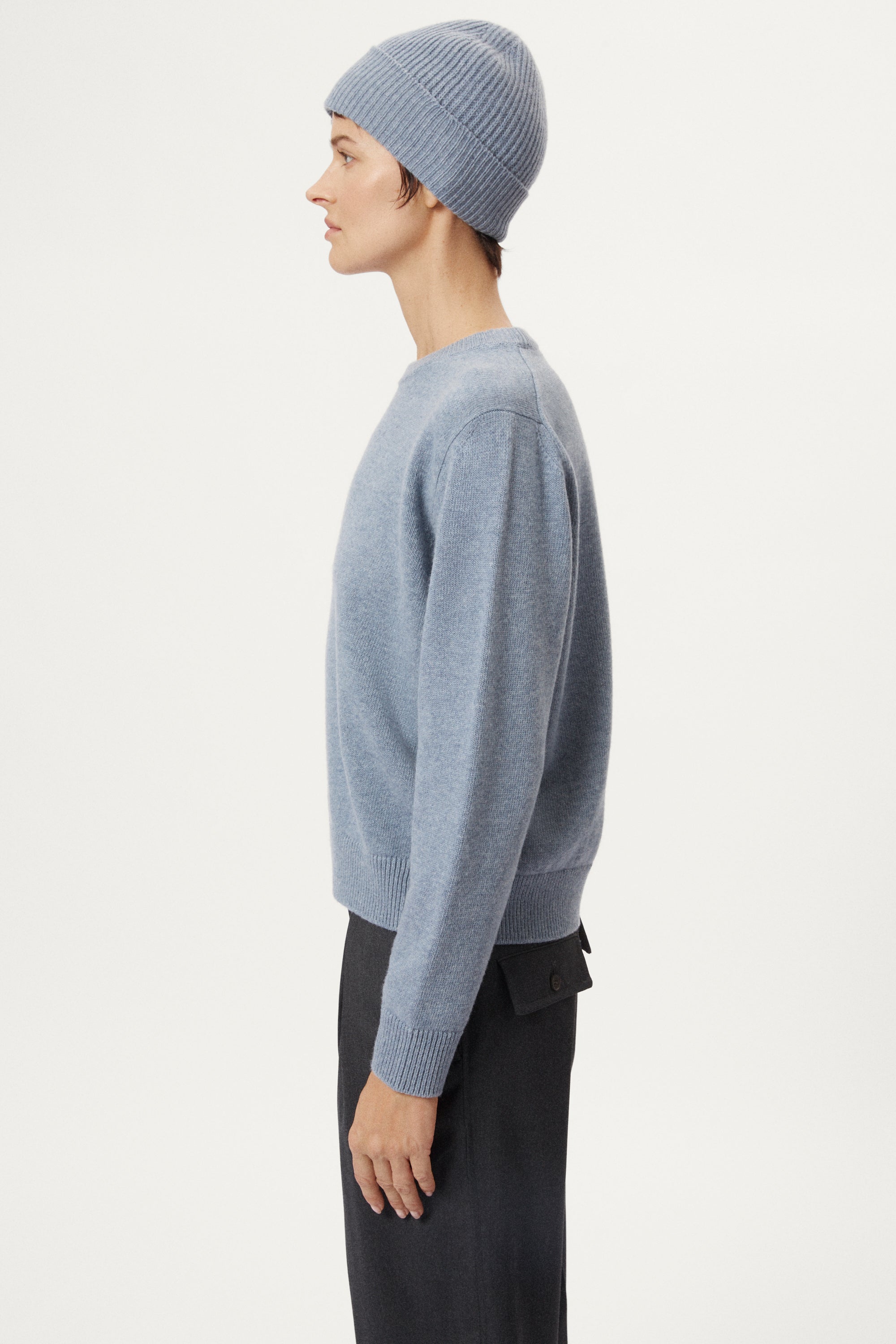 woman wearing a woolen light blue knit beanie and sweater against a white background