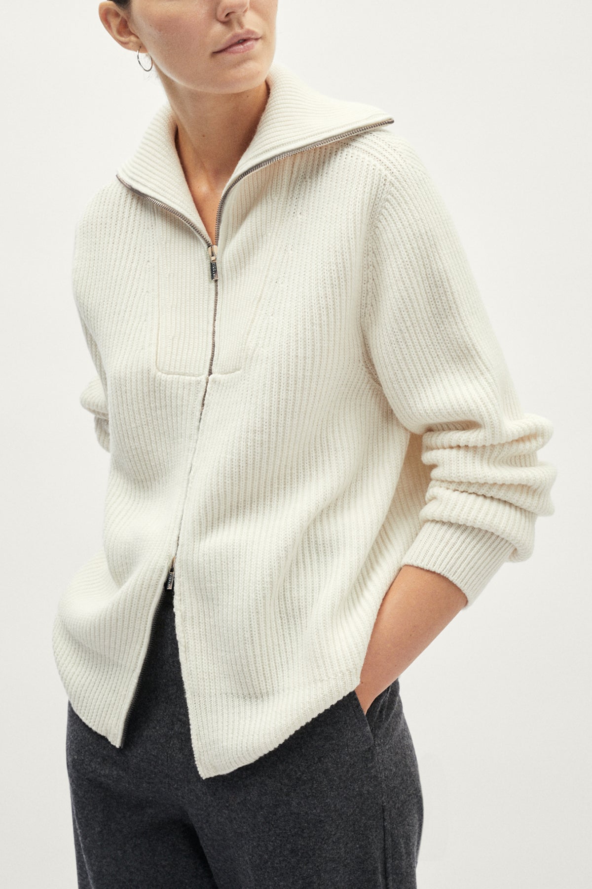 Person wearing a cream-colored sweater with a white background