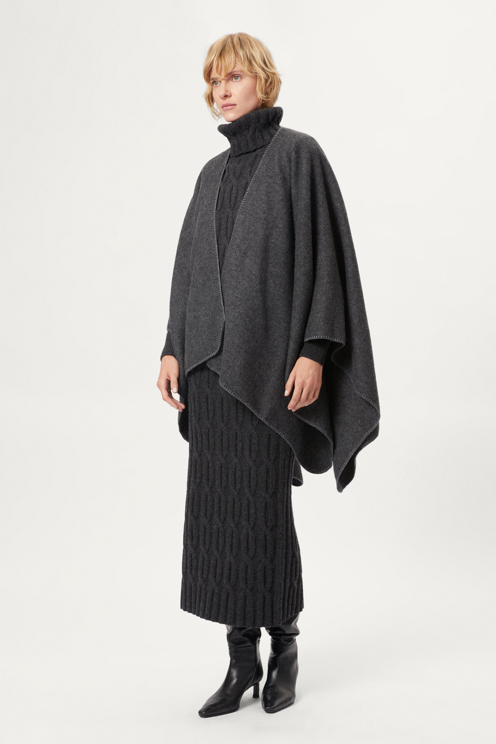 woman wearing a gray poncho over a grey outfit on a white background