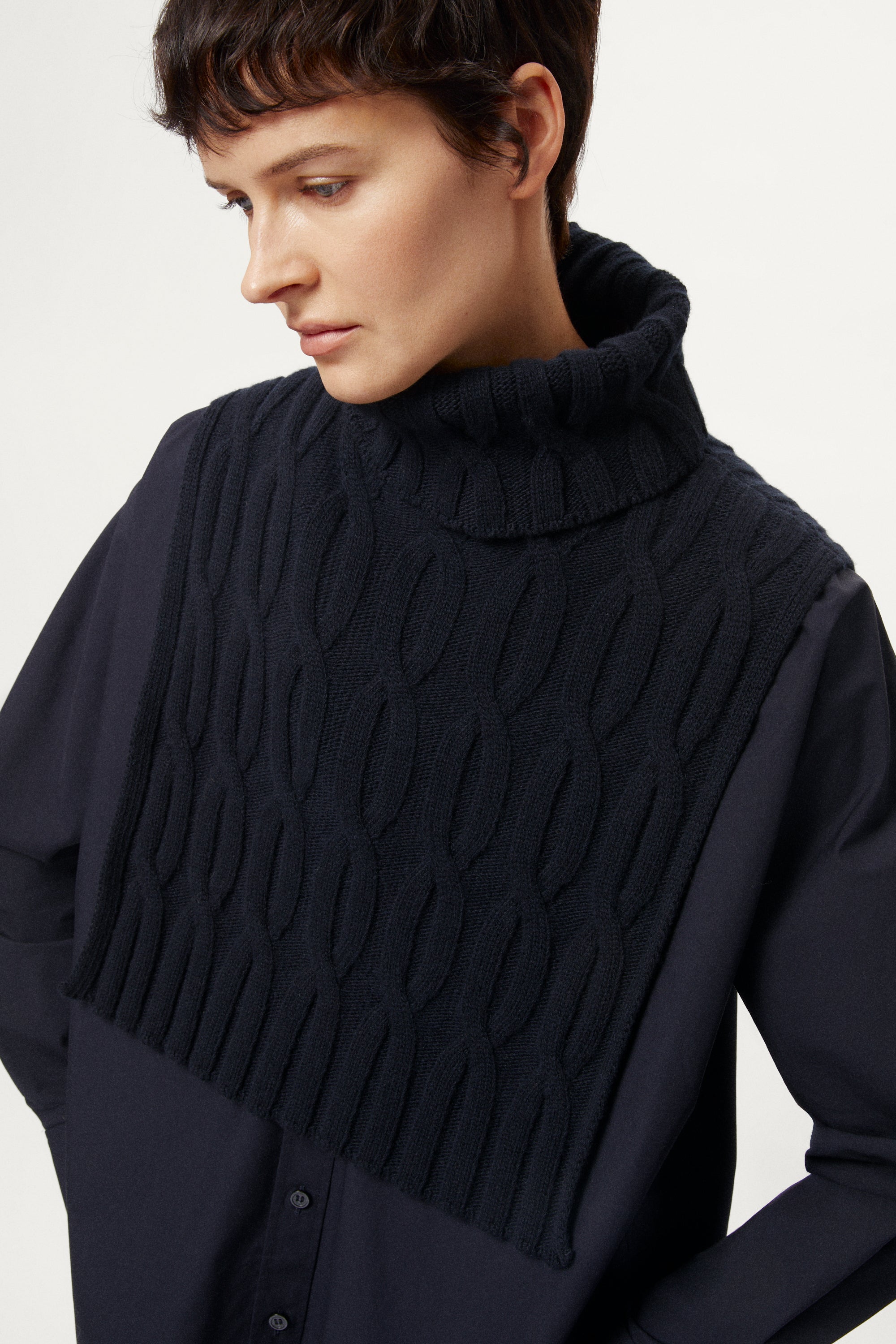 woman wearing a woolen dark blue cable knit with a plain background