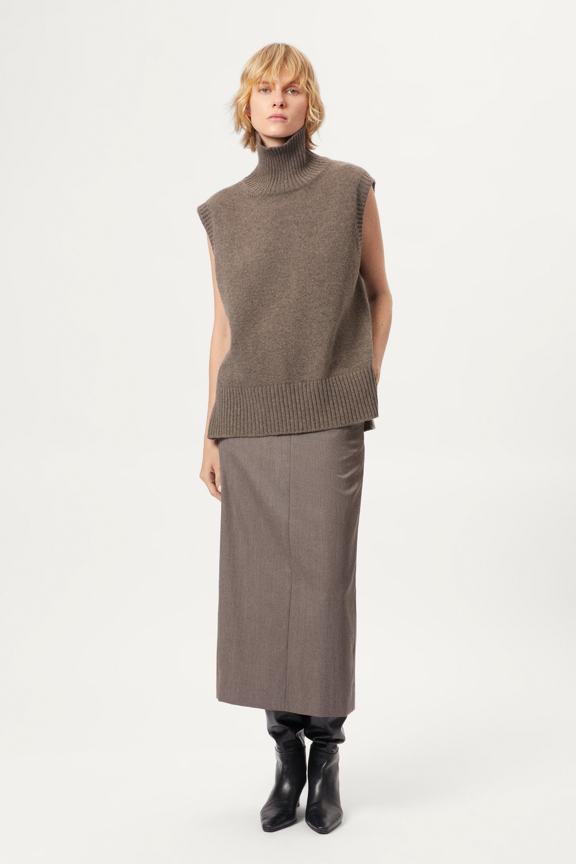 woman wearing a wool brown sleeveless high neck knitted top and skirt set on a white background