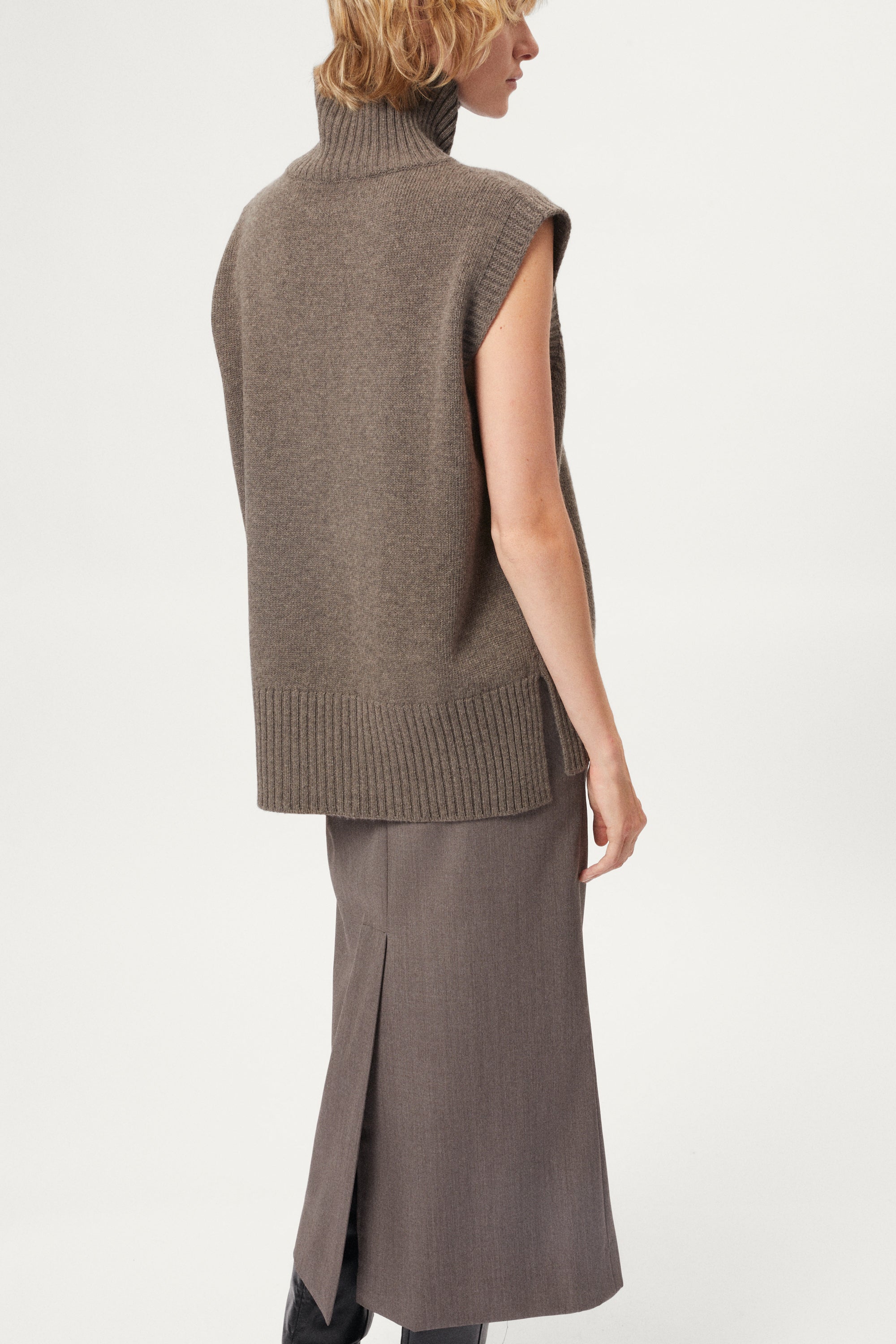 woman wearing a wool brown sleeveless high neck knitted top and skirt set on a white background