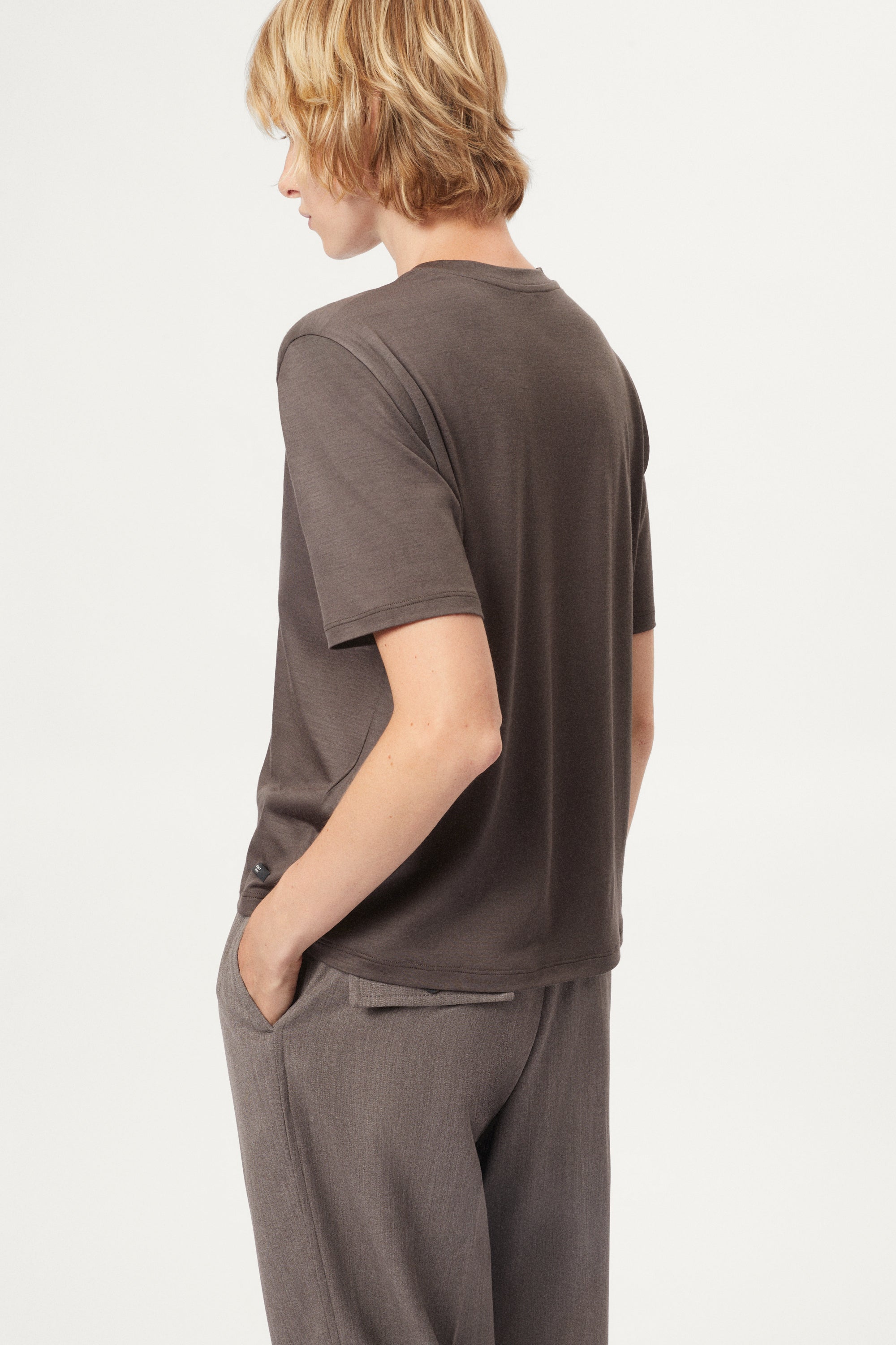 Person wearing a brown active wool t-shirt and pants on a white background