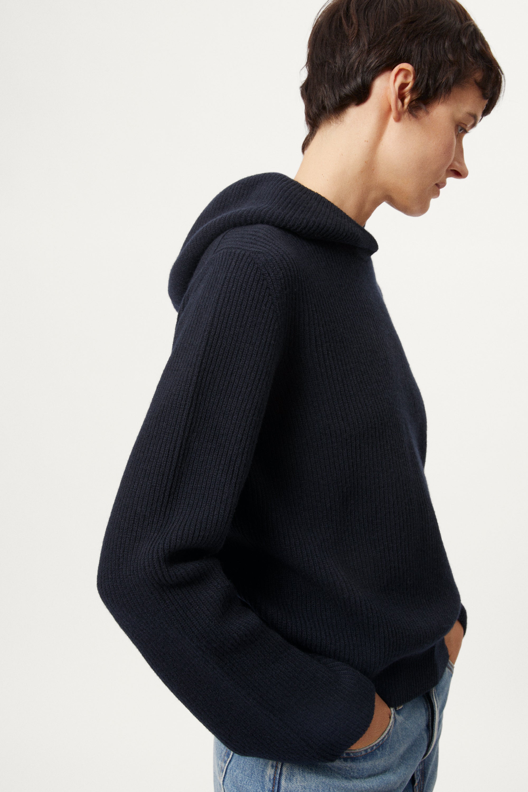 Person wearing a blue navy Woolen Ribbed Hoodie and blue jeans on a white background
