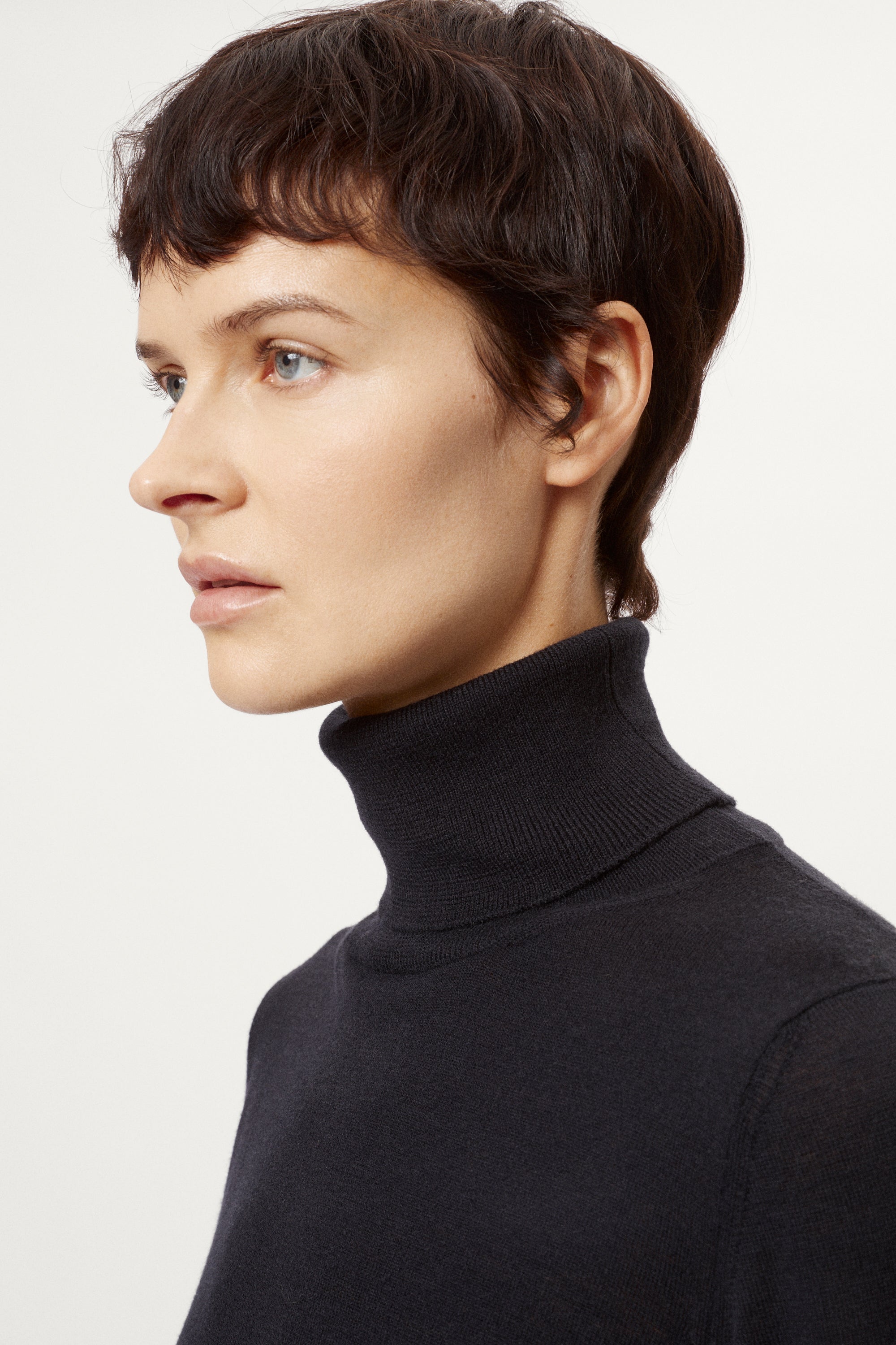 Person wearing a blue turtleneck sweater against a white background