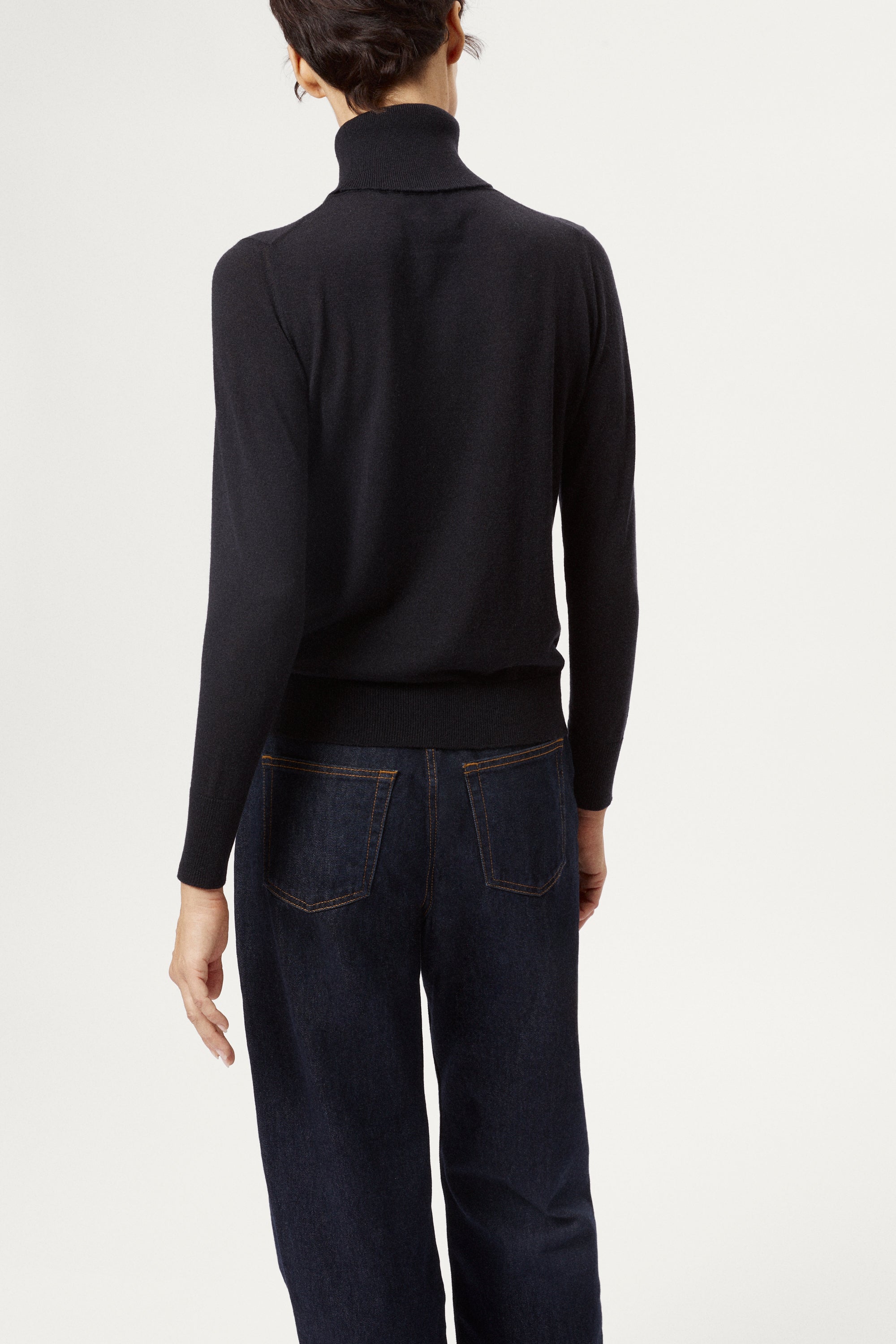 Person wearing a blue turtleneck sweater against a white background