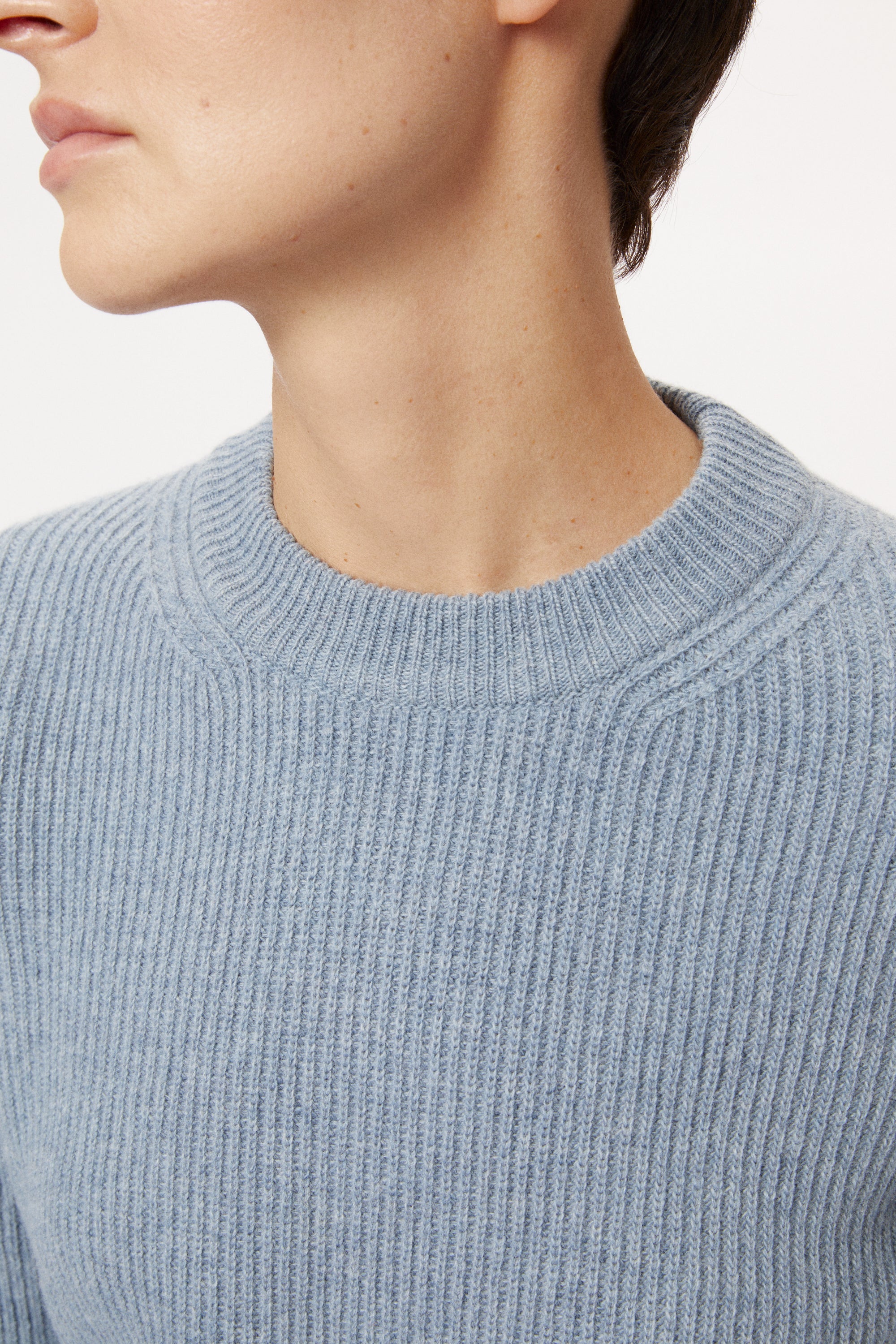 Woman wearing a wool light blue sweater on a white background