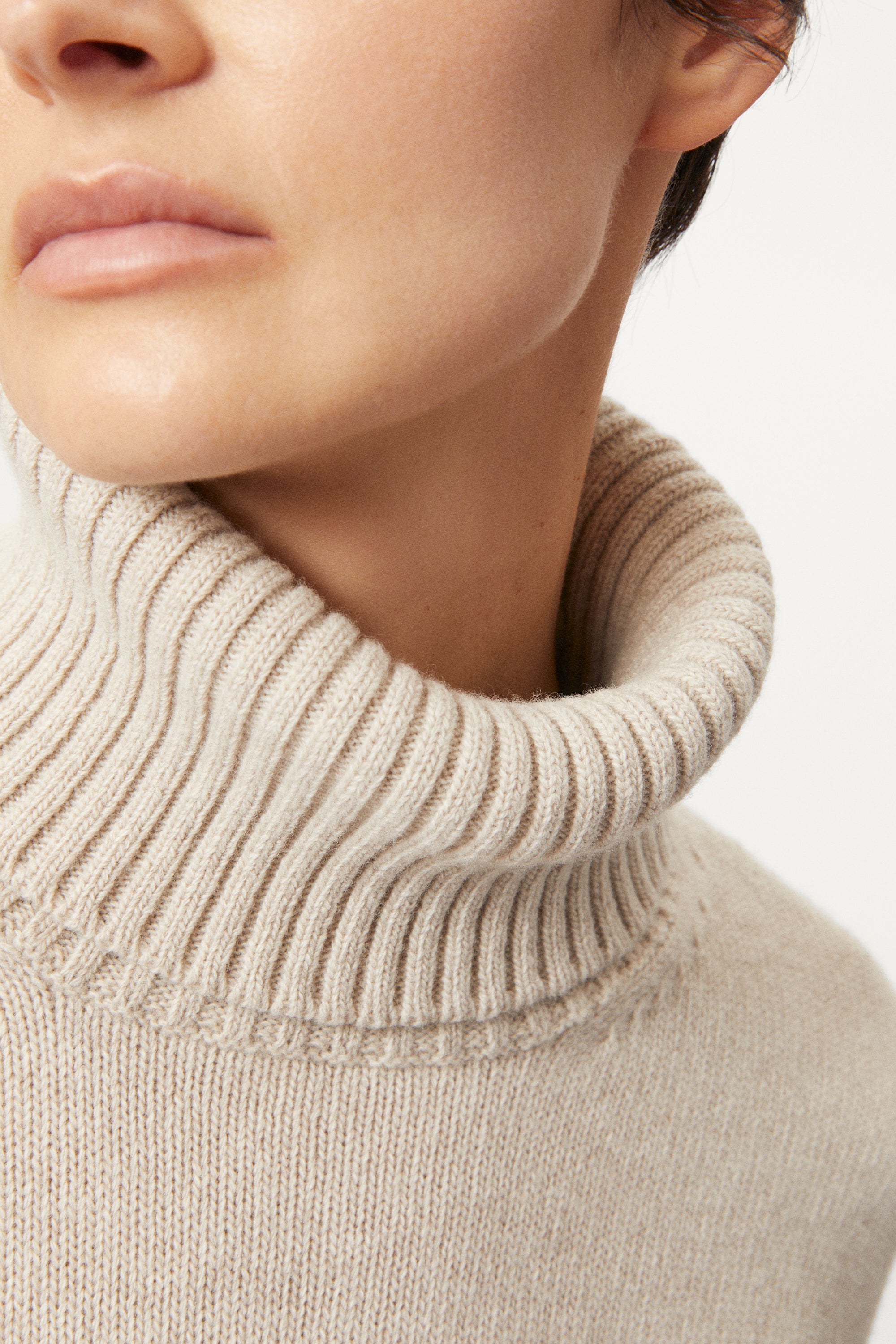 woman wearing a woolen beige sweater and wool pants on a white background