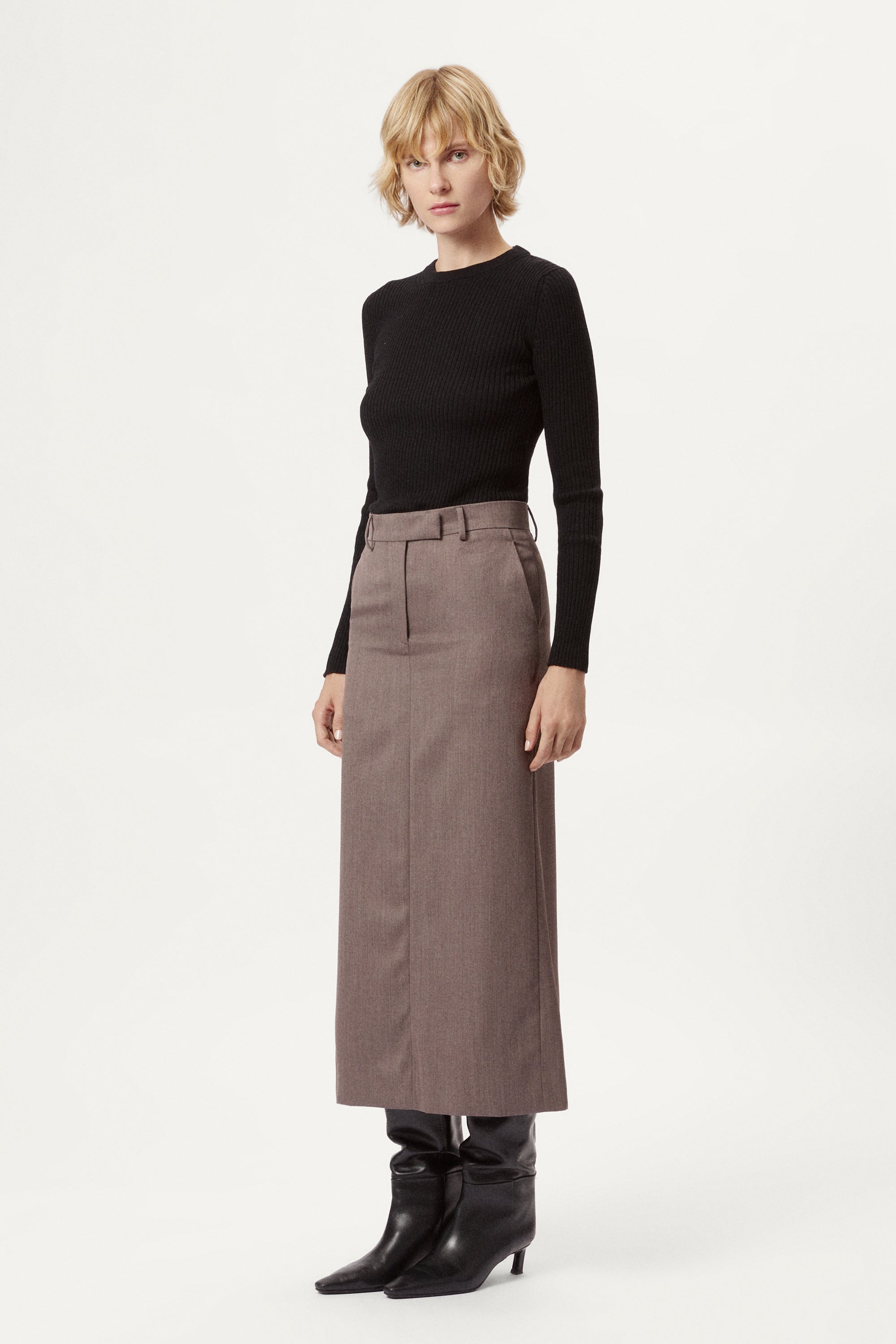 Woman wearing a black top and brown skirt on a white background