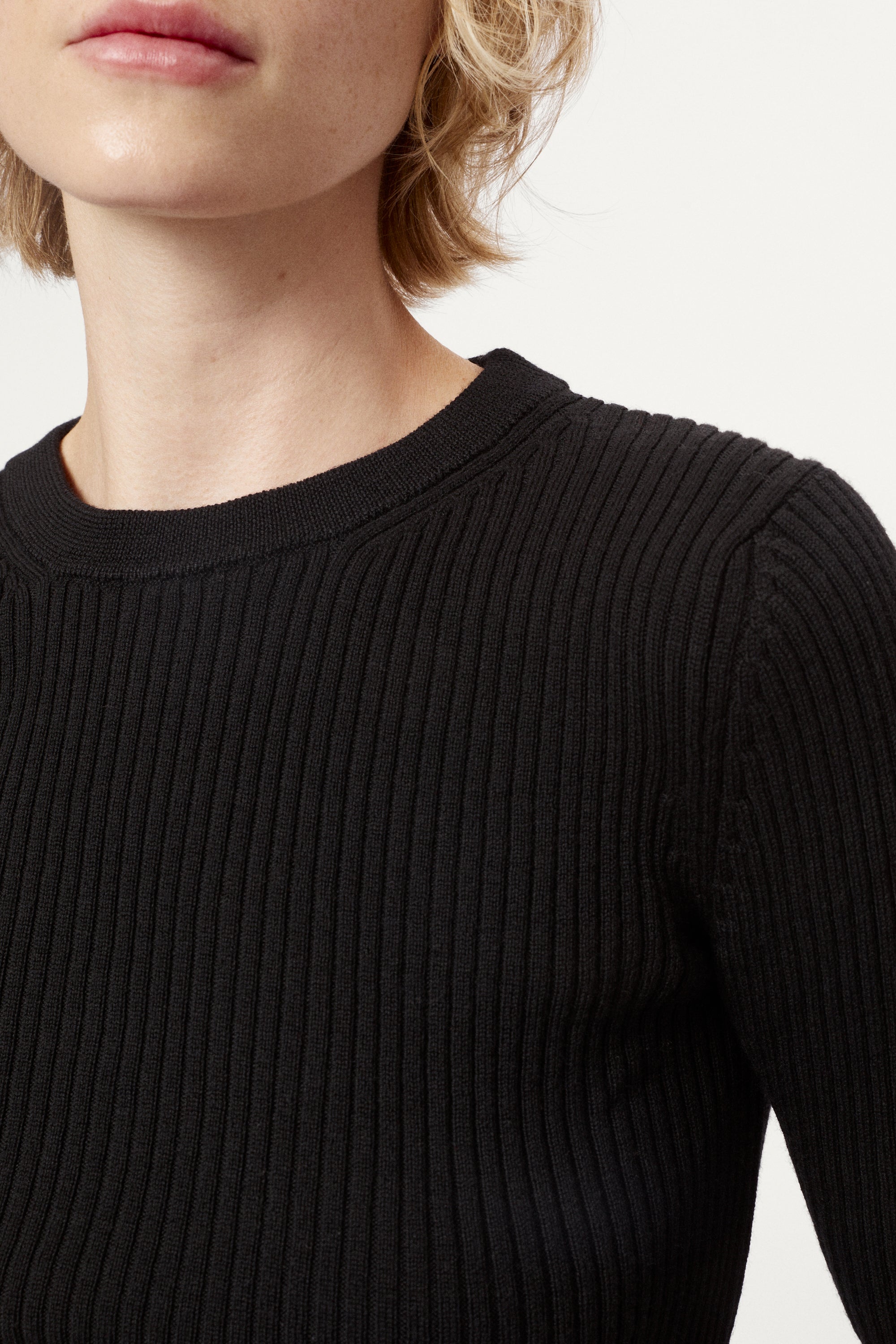Woman wearing a black top and brown skirt on a white background