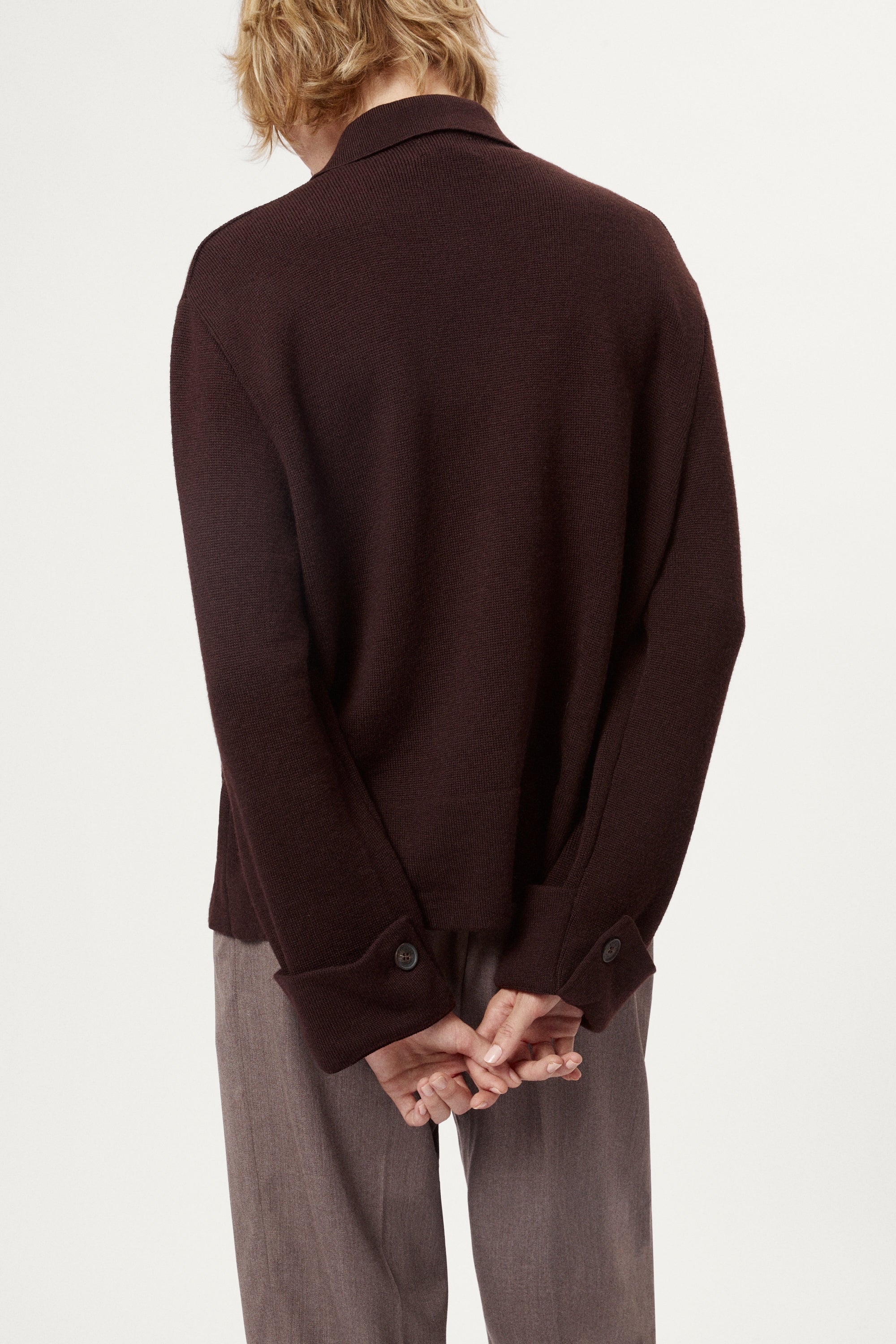 Woman wearing a dark brown jacket and pants on a white background