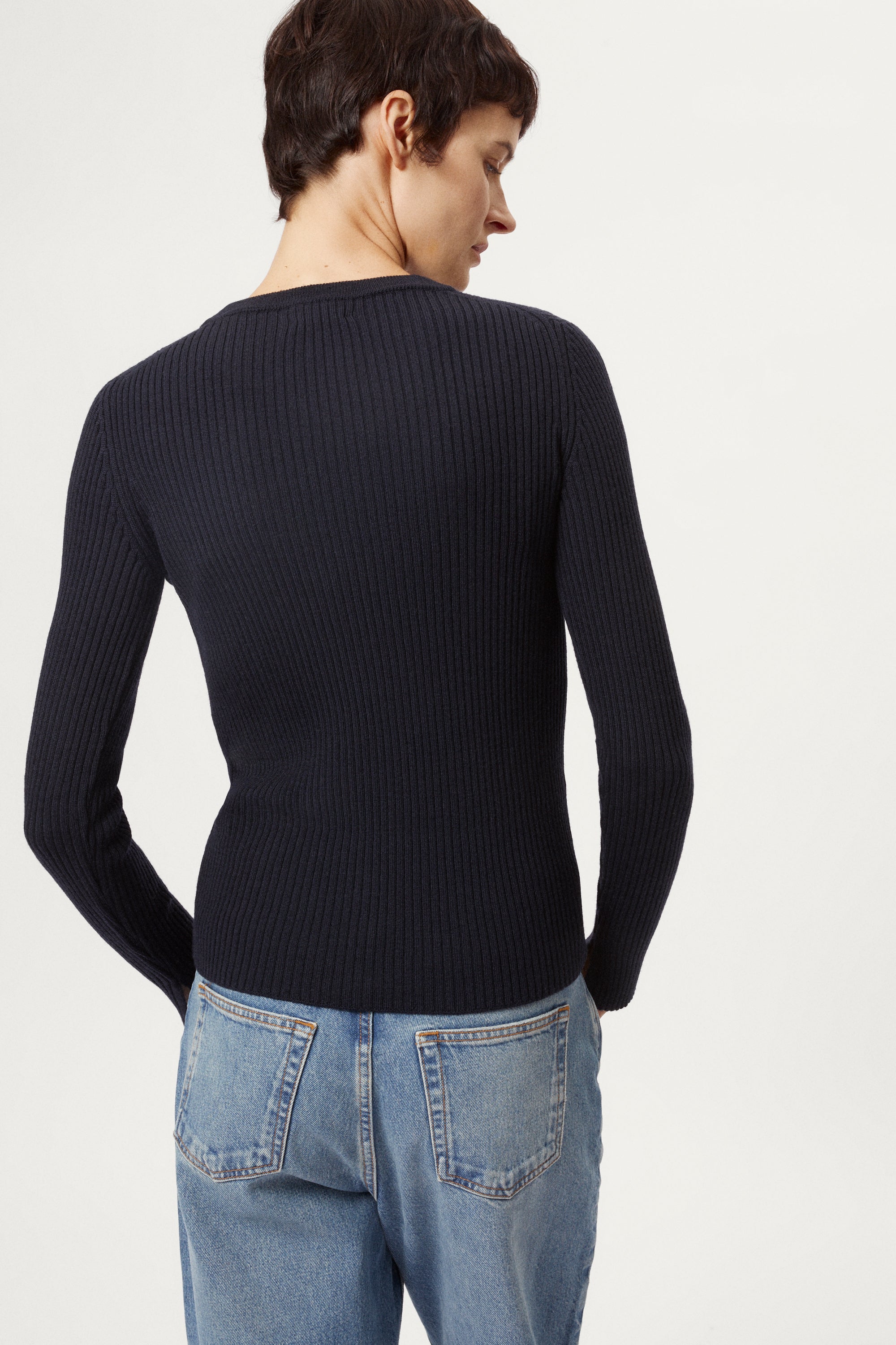 Woman wearing a blue sweater and light blue jeans on a white background