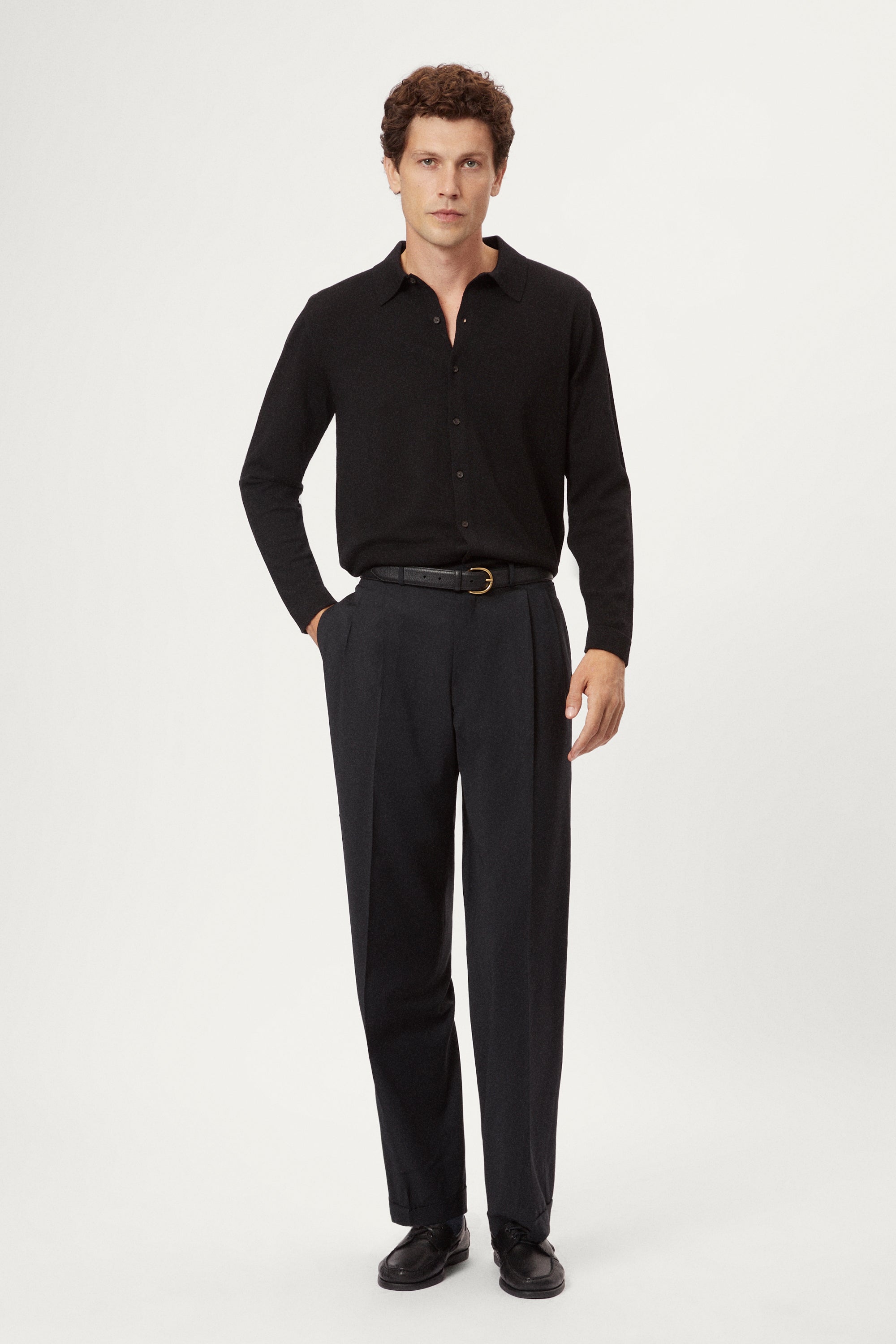 Man wearing a black shirt and grey pants on a white background