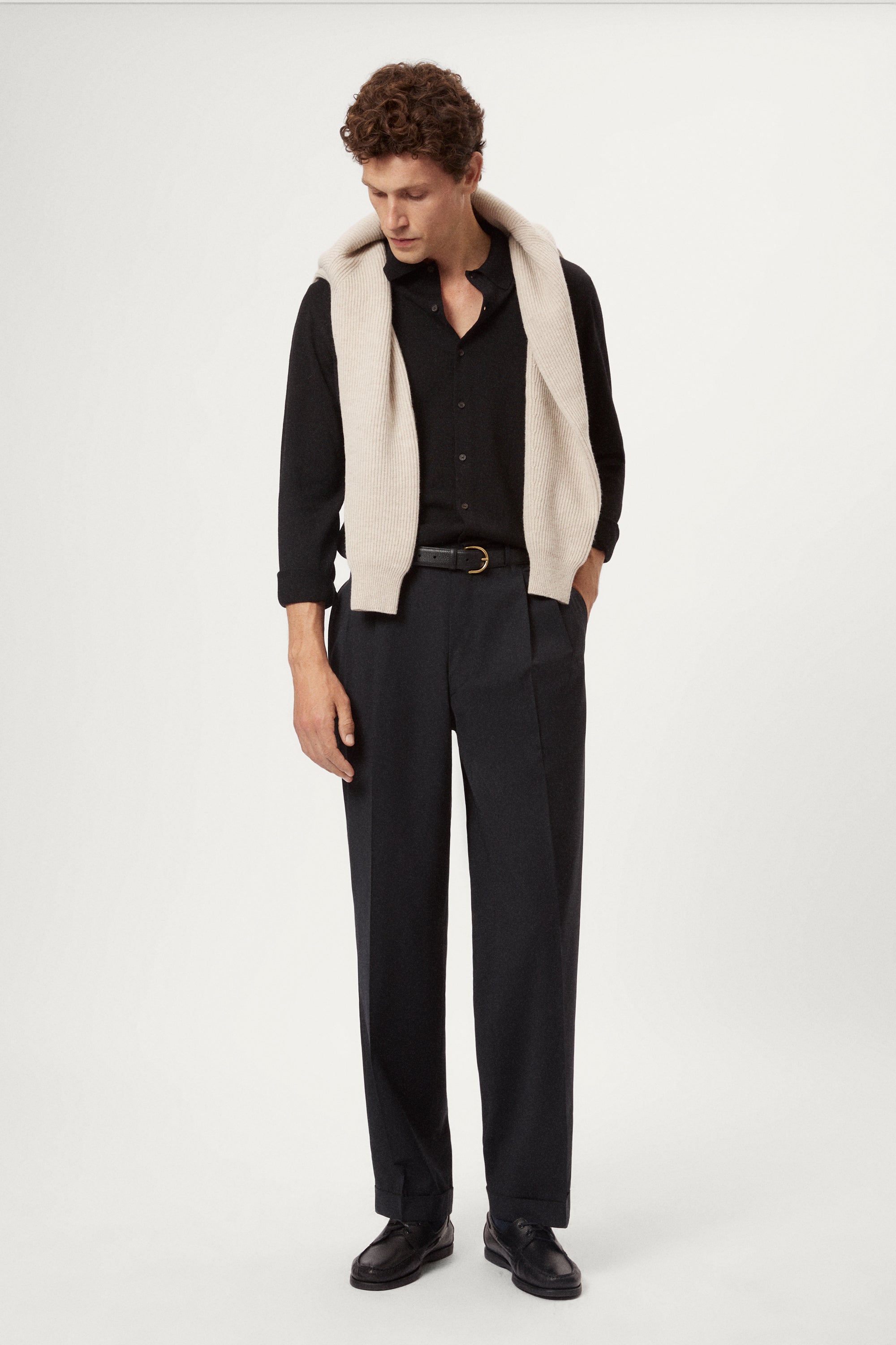 Man wearing a black shirt and grey pants on a white background