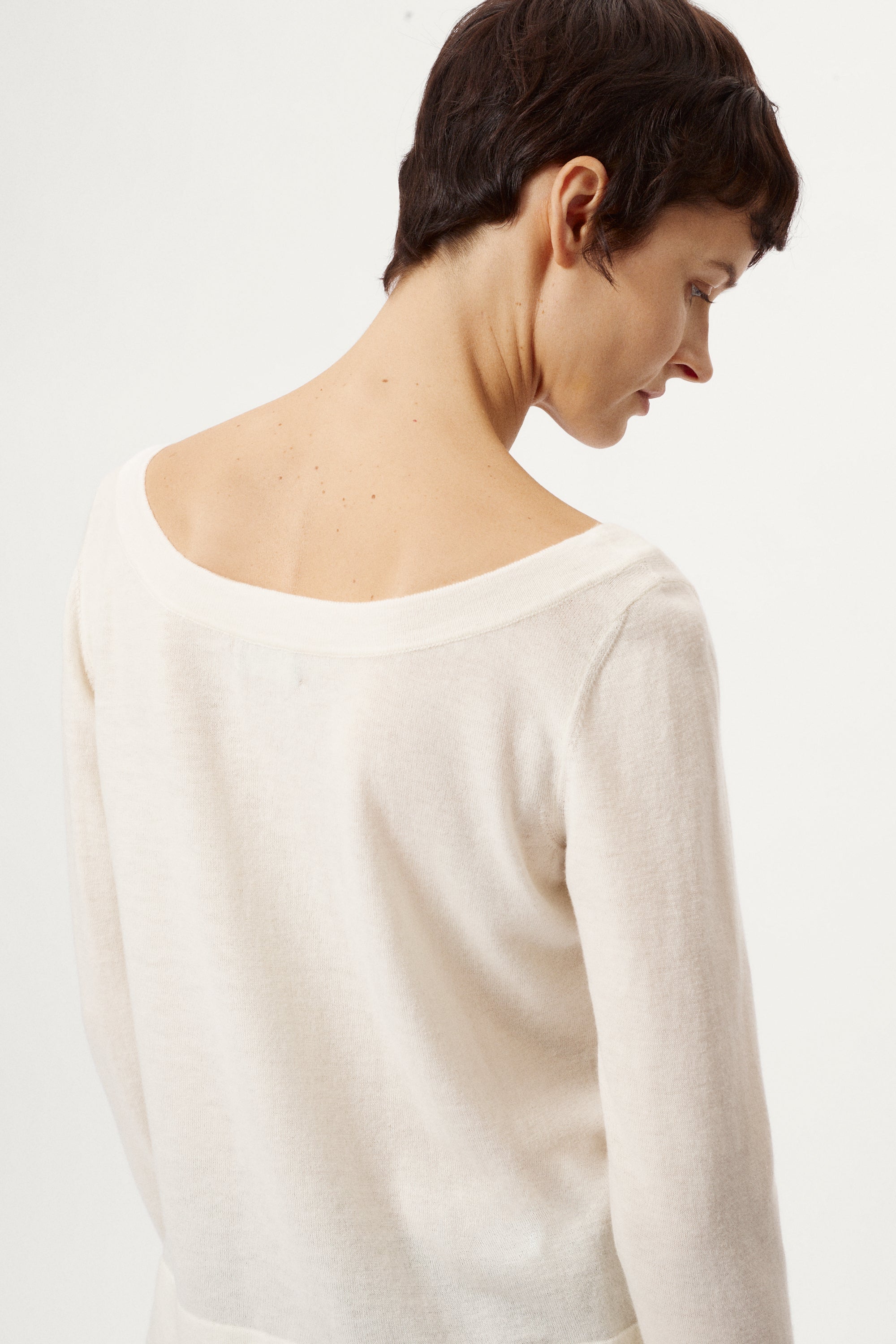 Person wearing a white sweater and black pants on a white background