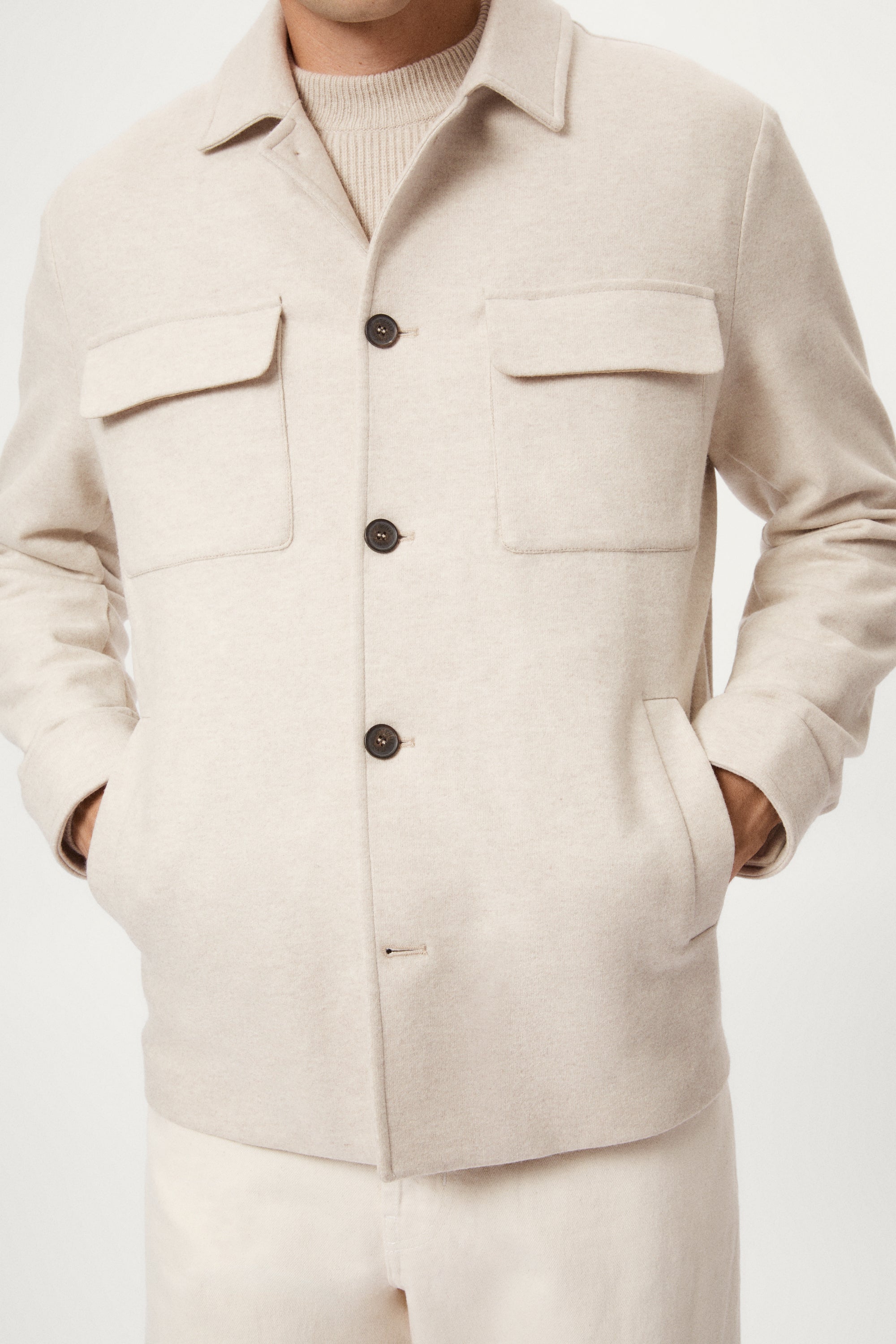 Man wearing a woolen ecru jacket with button details on a white background