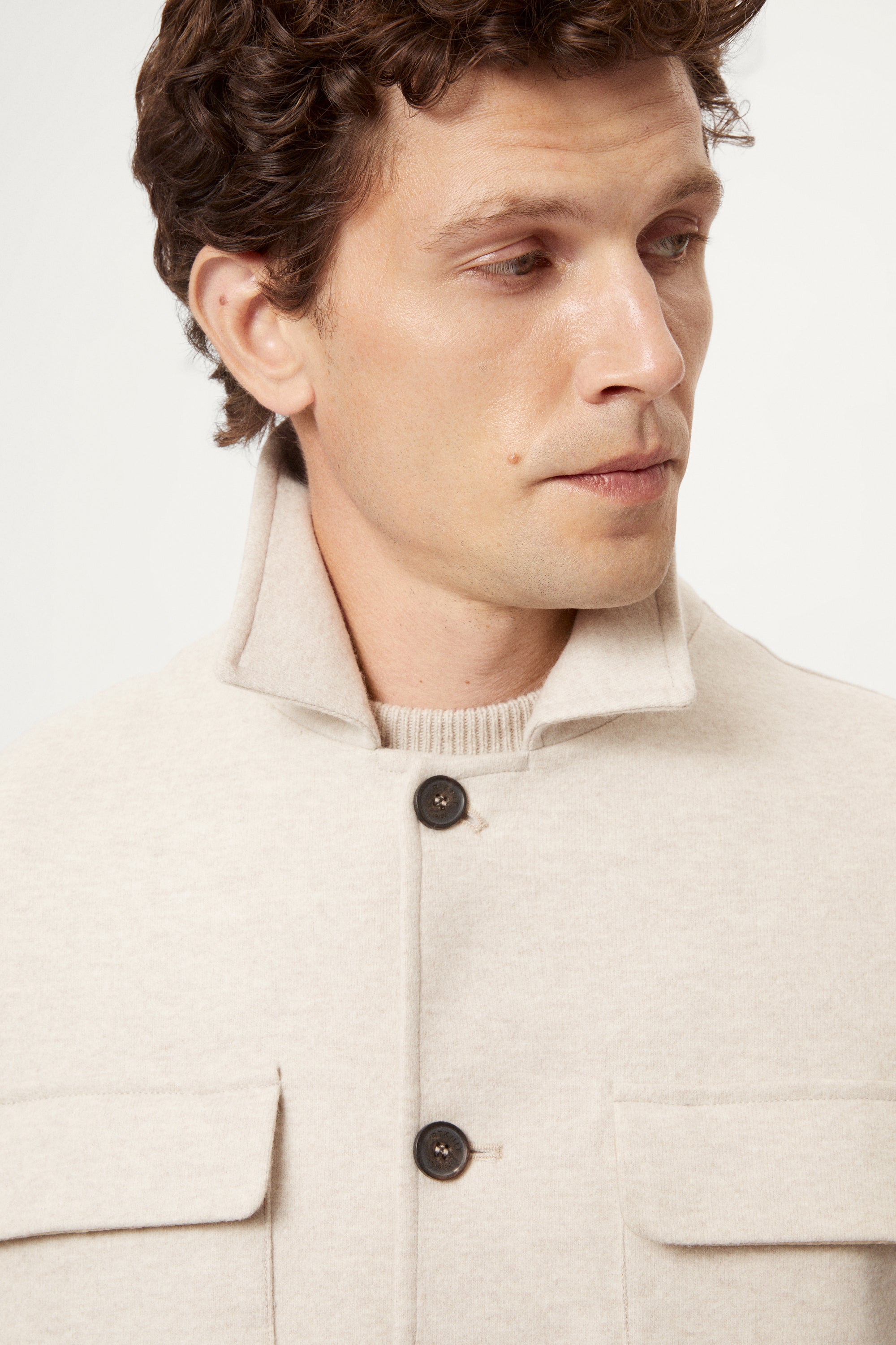 Man wearing a woolen ecru jacket with button details on a white background