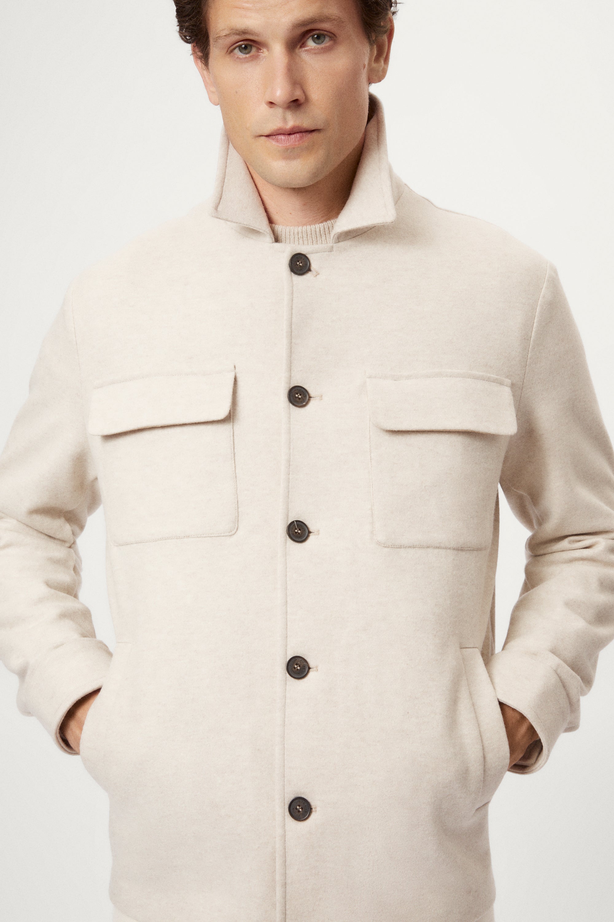 Man wearing a woolen ecru jacket with button details on a white background