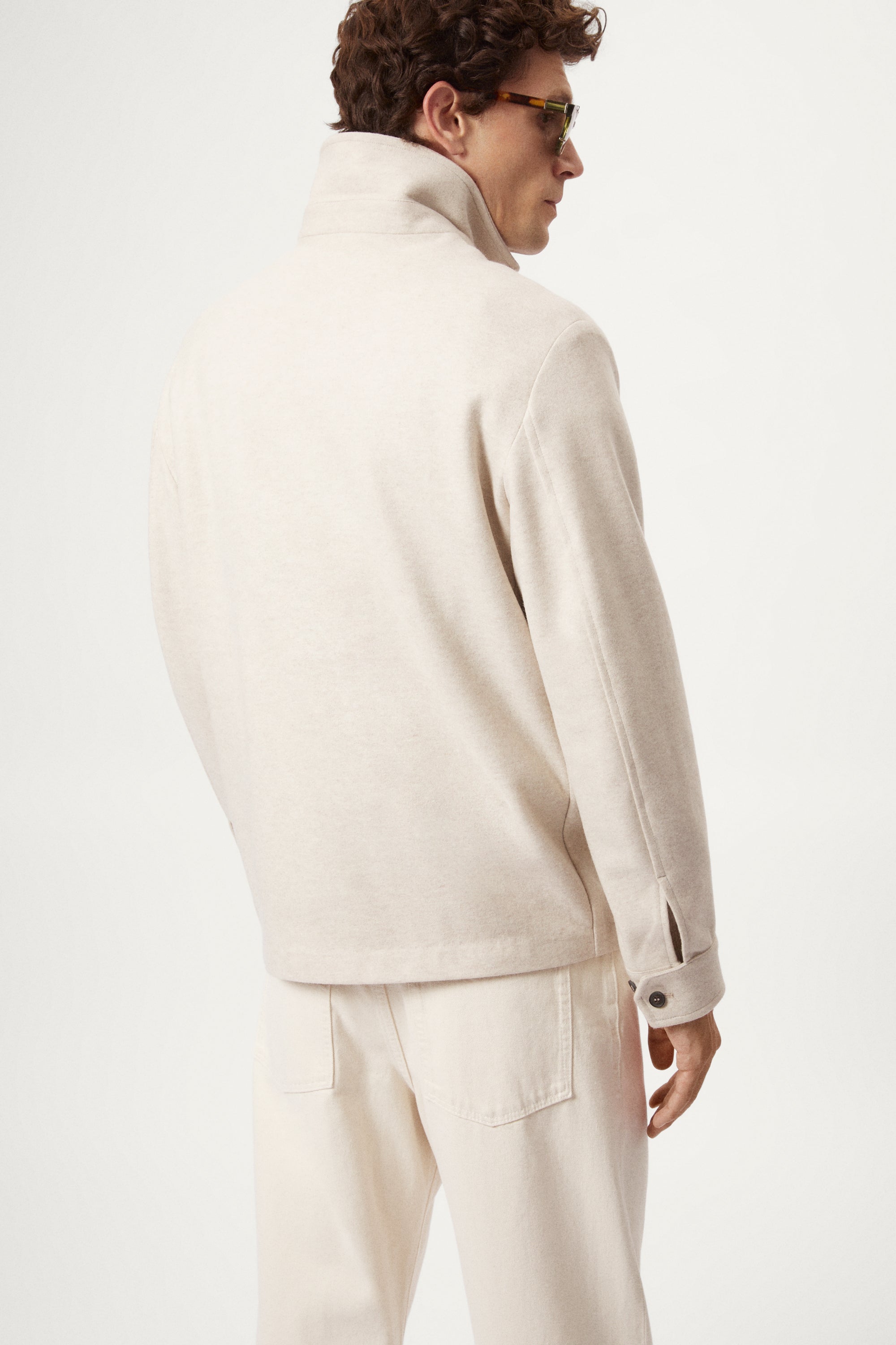 Man wearing a woolen ecru jacket with button details on a white background