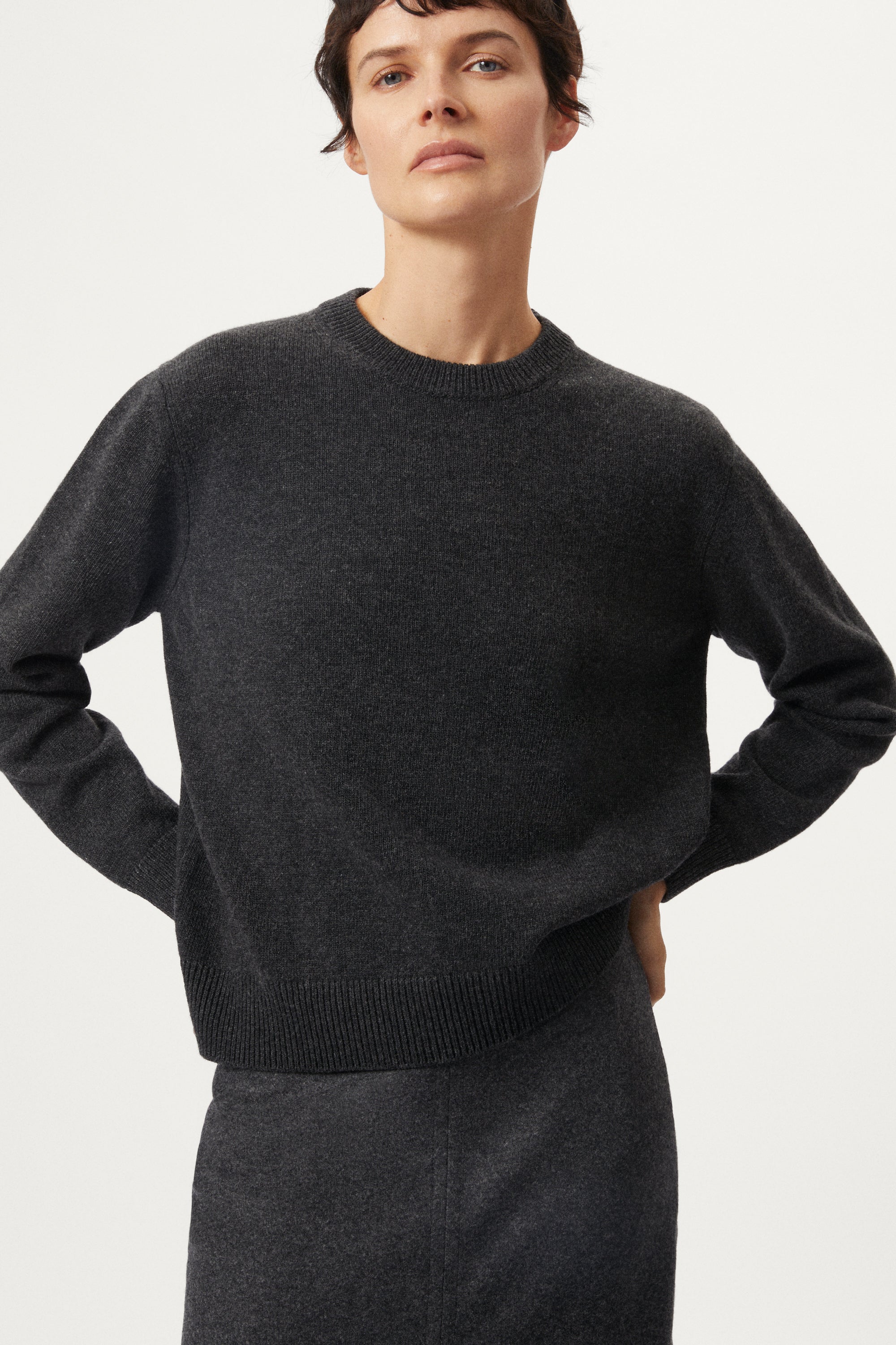 woman wearing a dark gray Woolen Plain Stitch Sweaterr on a light gray background