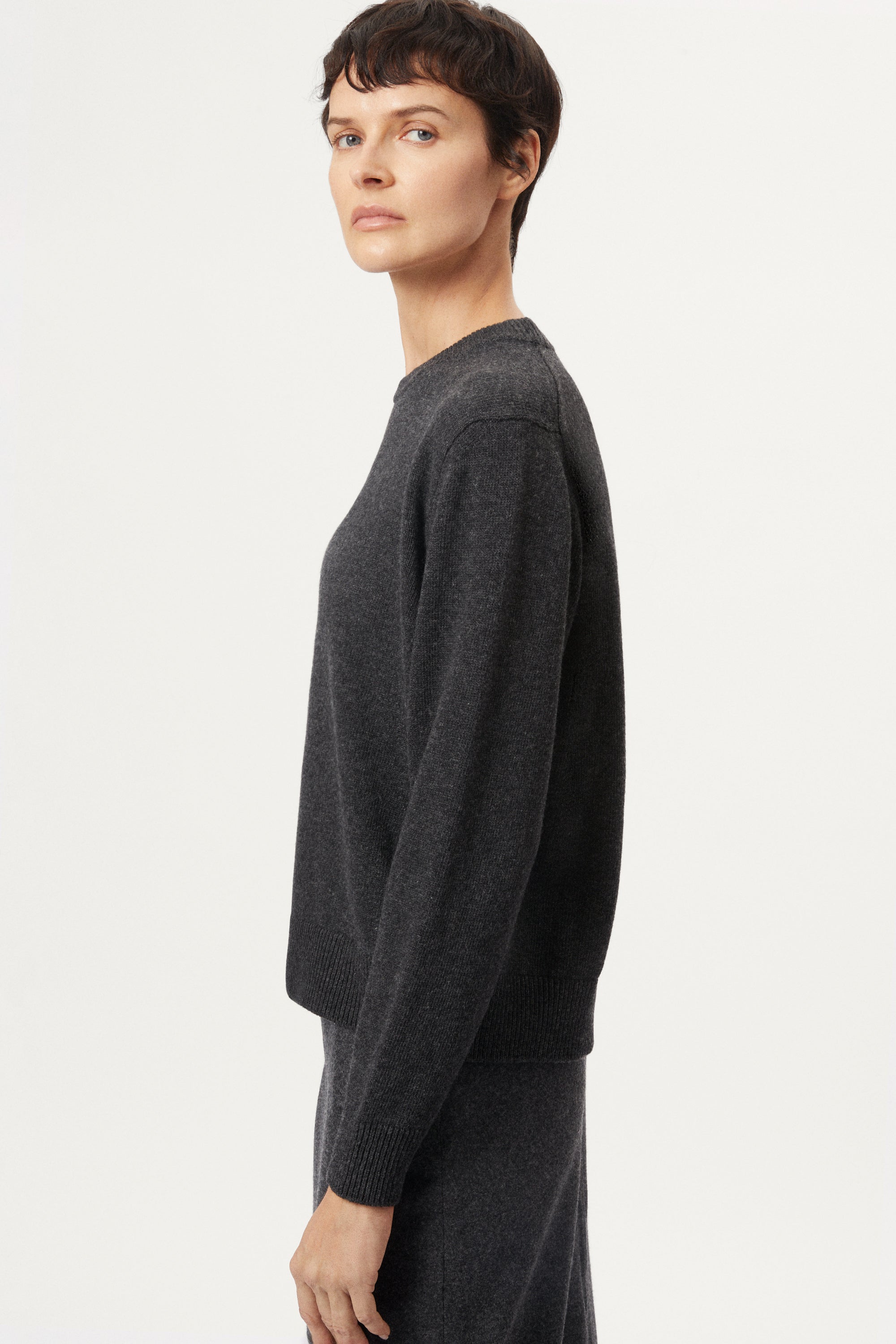 woman wearing a dark gray Woolen Plain Stitch Sweaterr on a light gray background