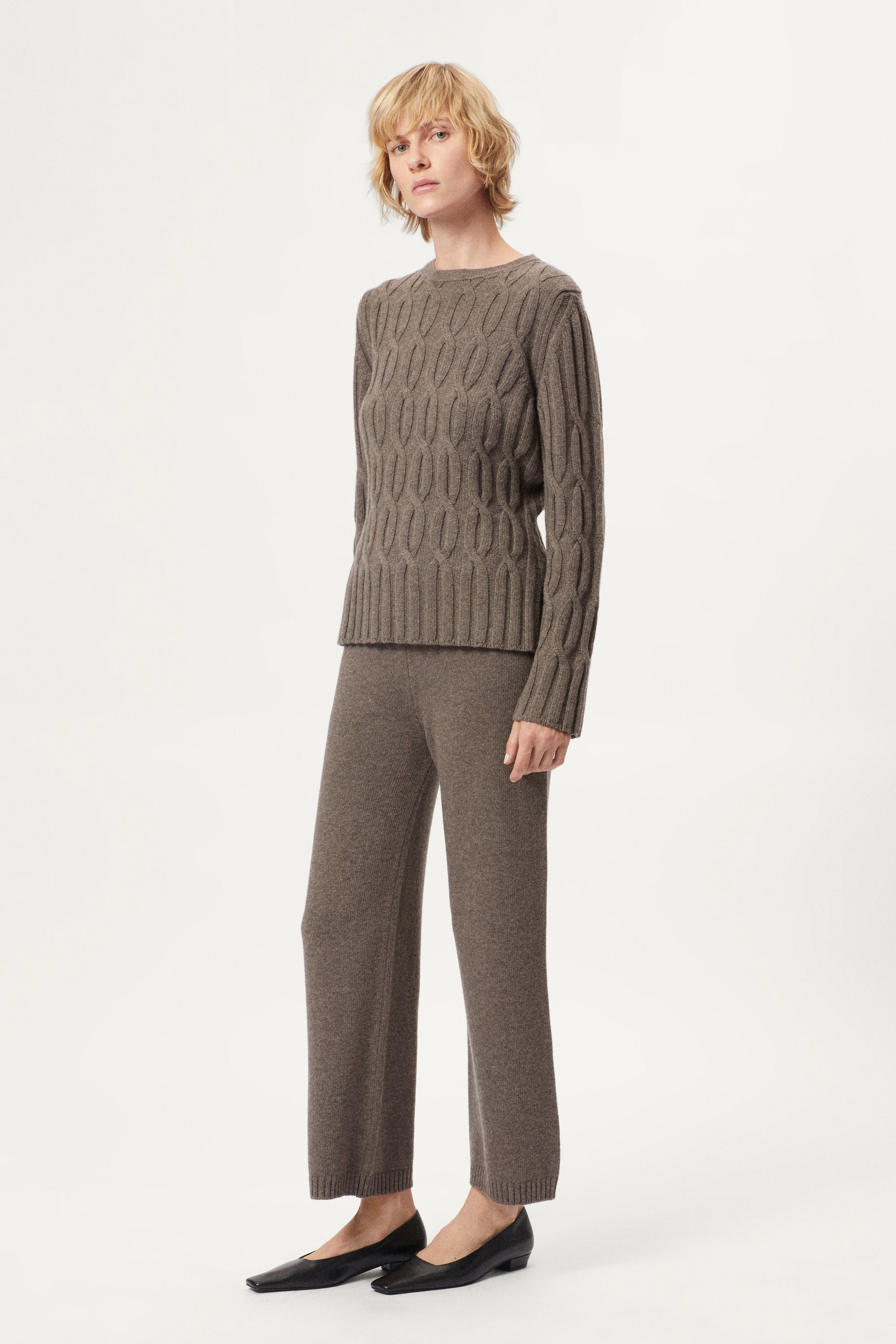 Woman wearing a brown cable knit sweater and matching taupe woolen knitted pants