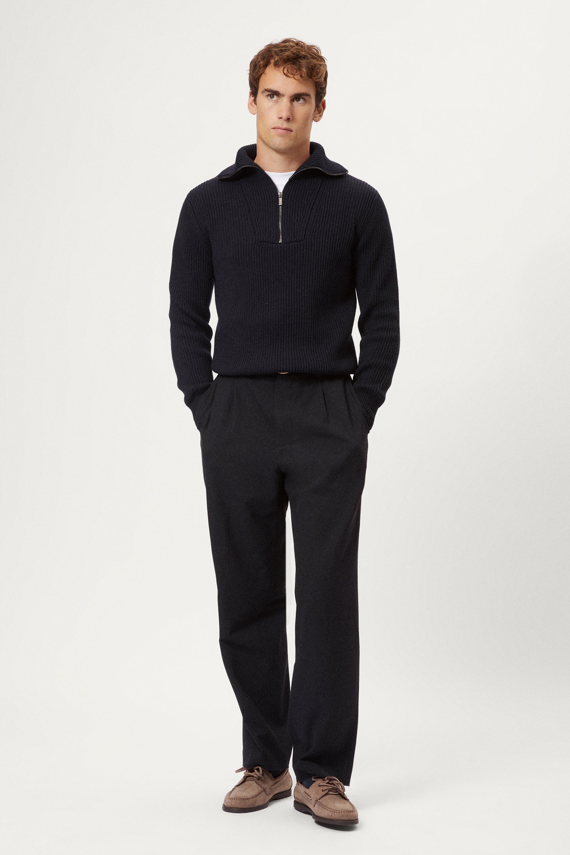 Man wearing a dark blue merino half zip sweater with a white background