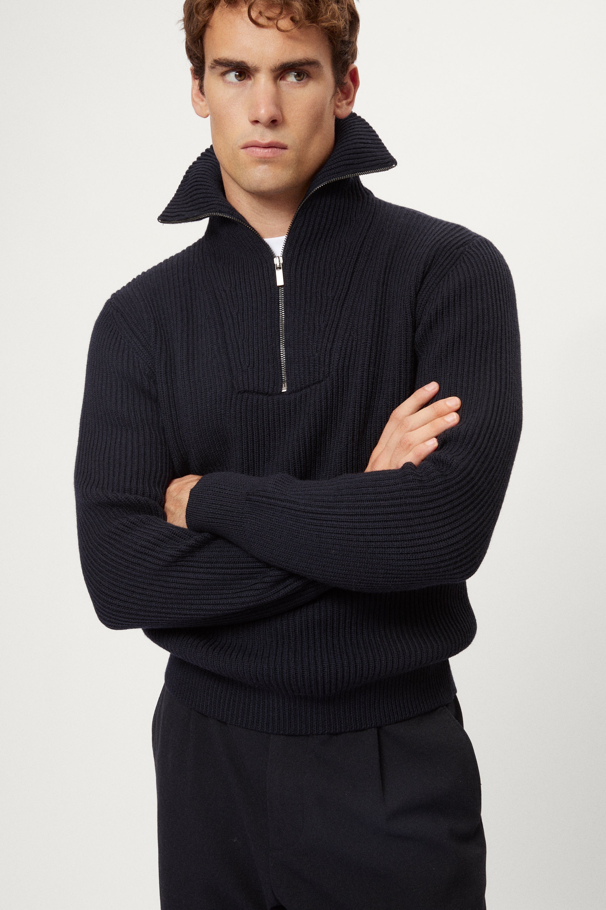 Man wearing a dark blue merino half zip sweater with a white background