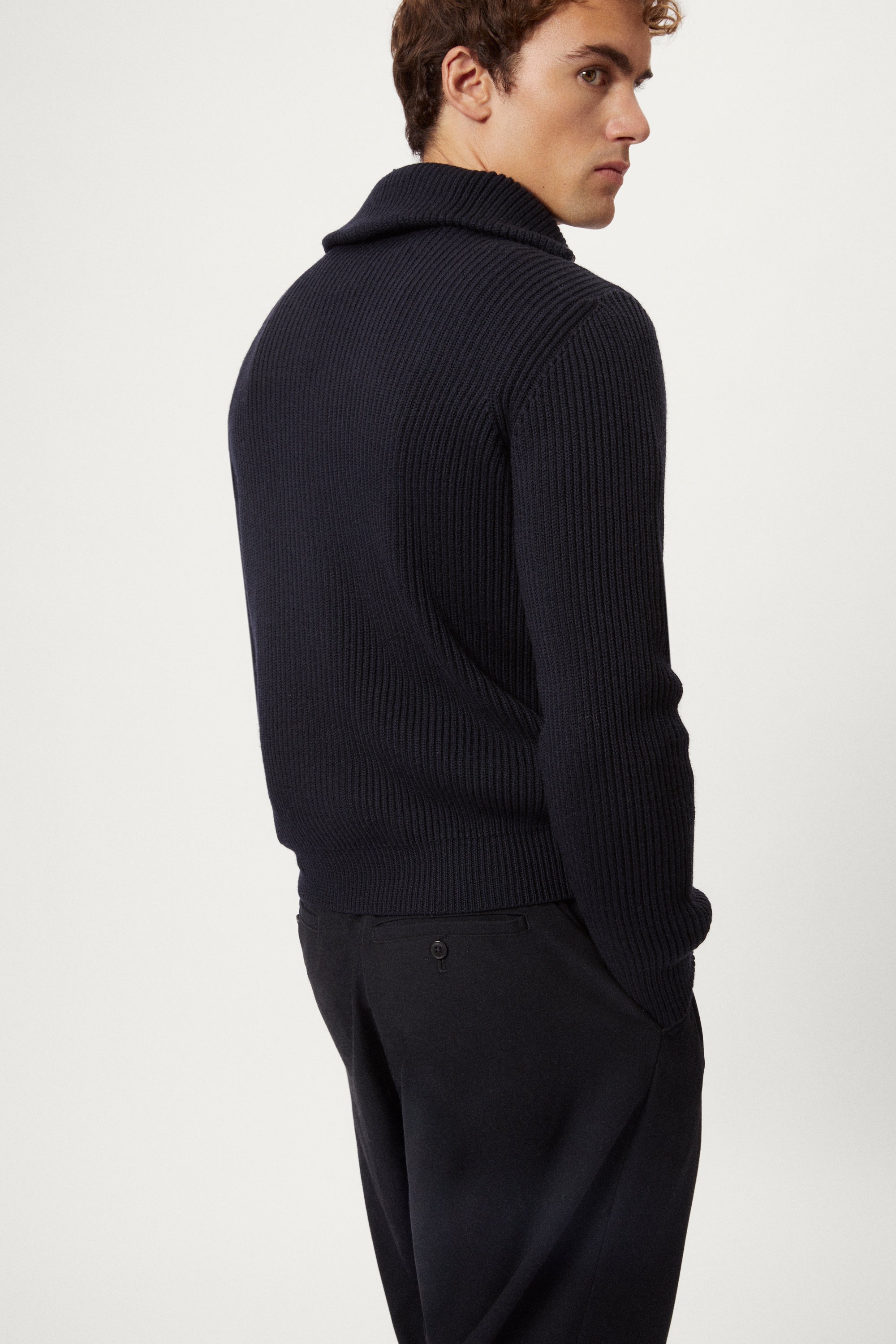 Man wearing a dark blue merino half zip sweater with a white background