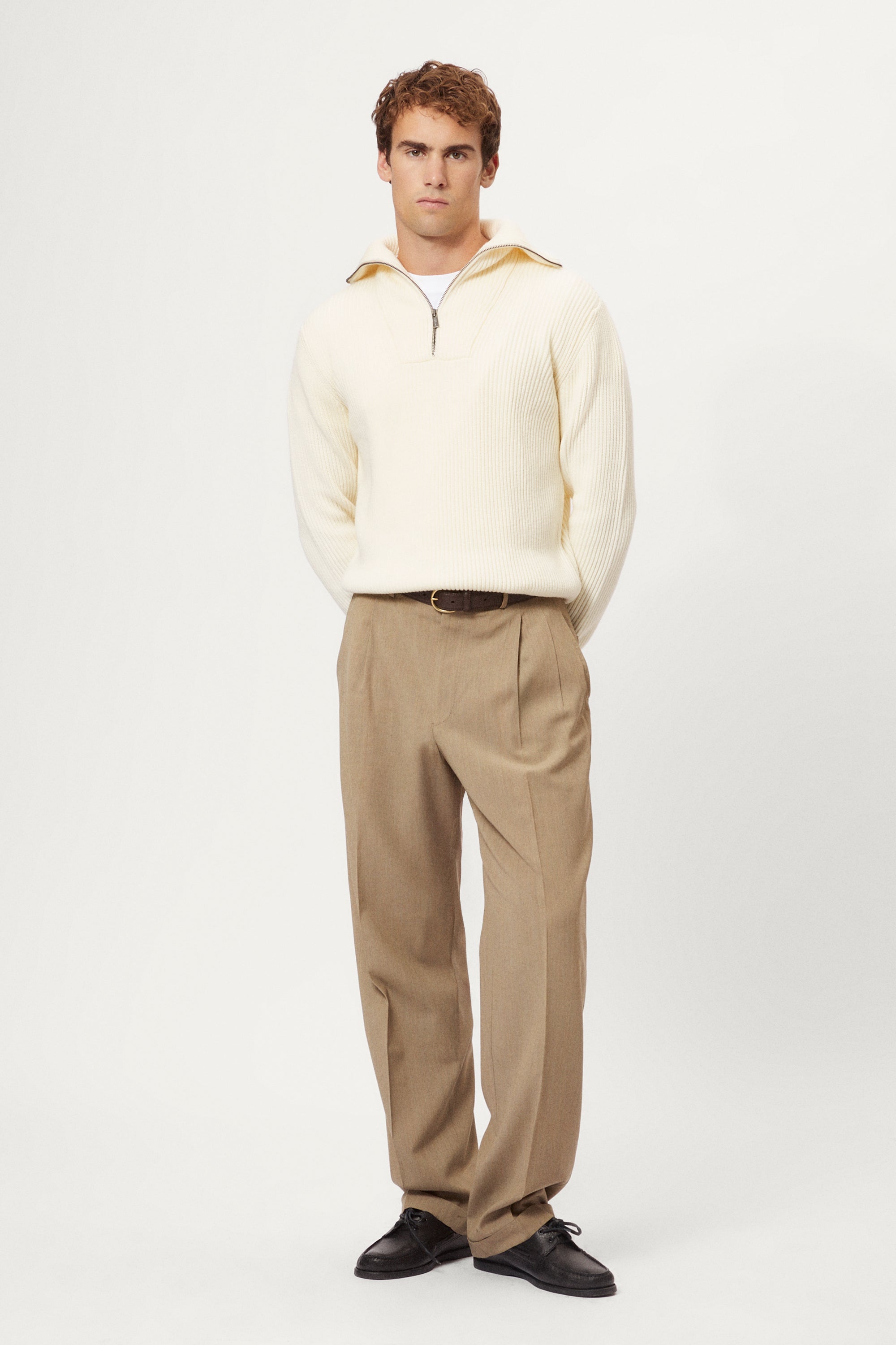 Man wearing a cream half-zip sweater against a white background