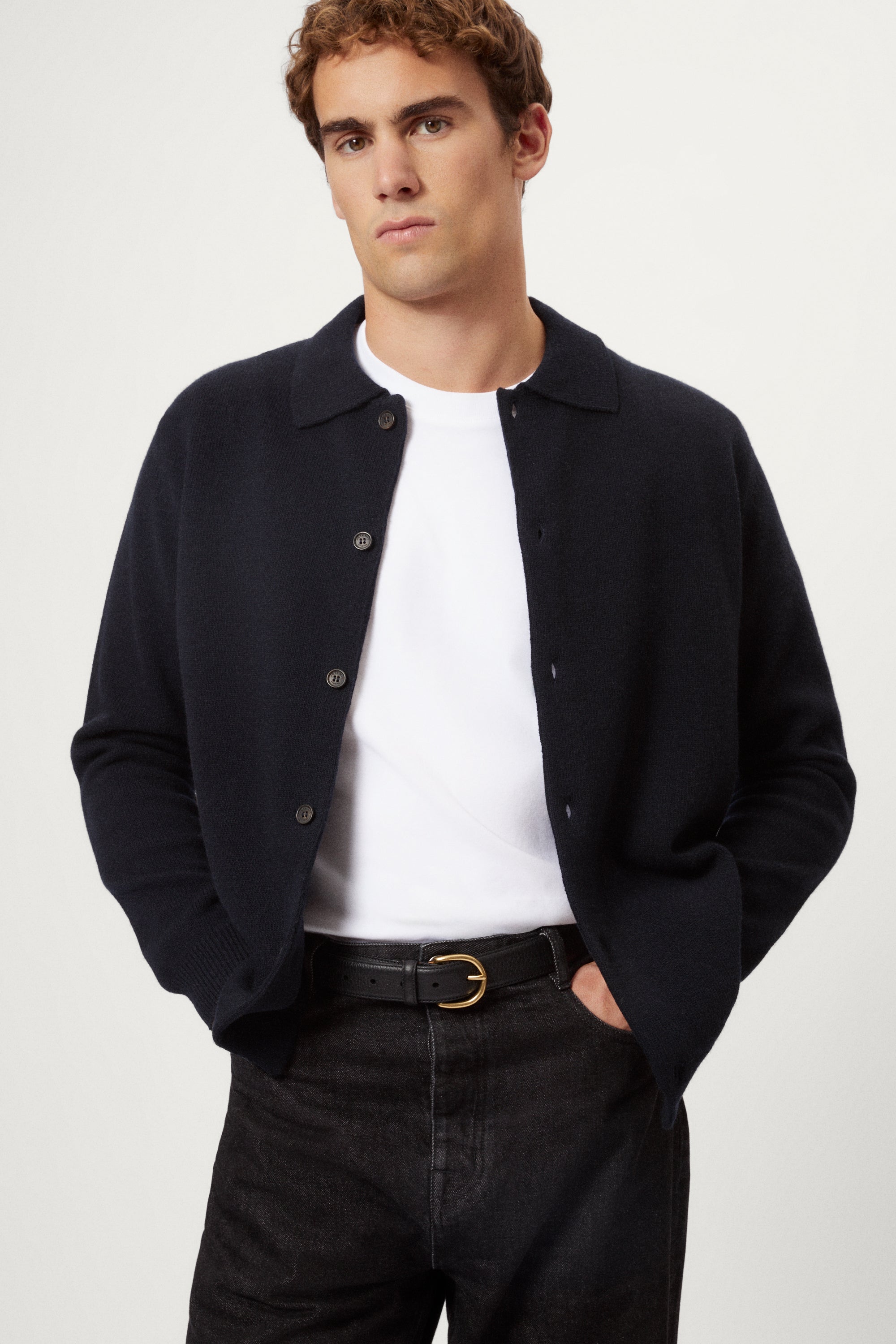 Man wearing a black wool shirt over a white shirt with a plain background