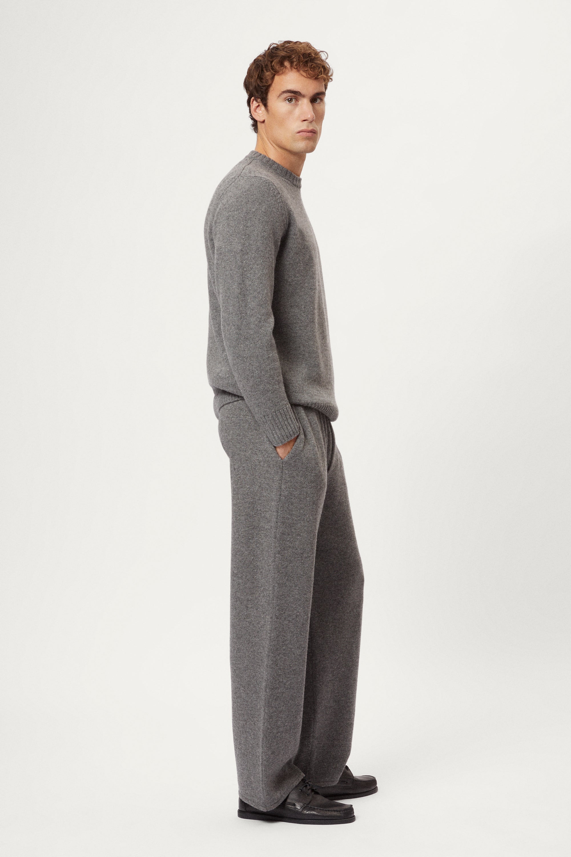 Person wearing a woolen gray knit pants and black shoes on a white background