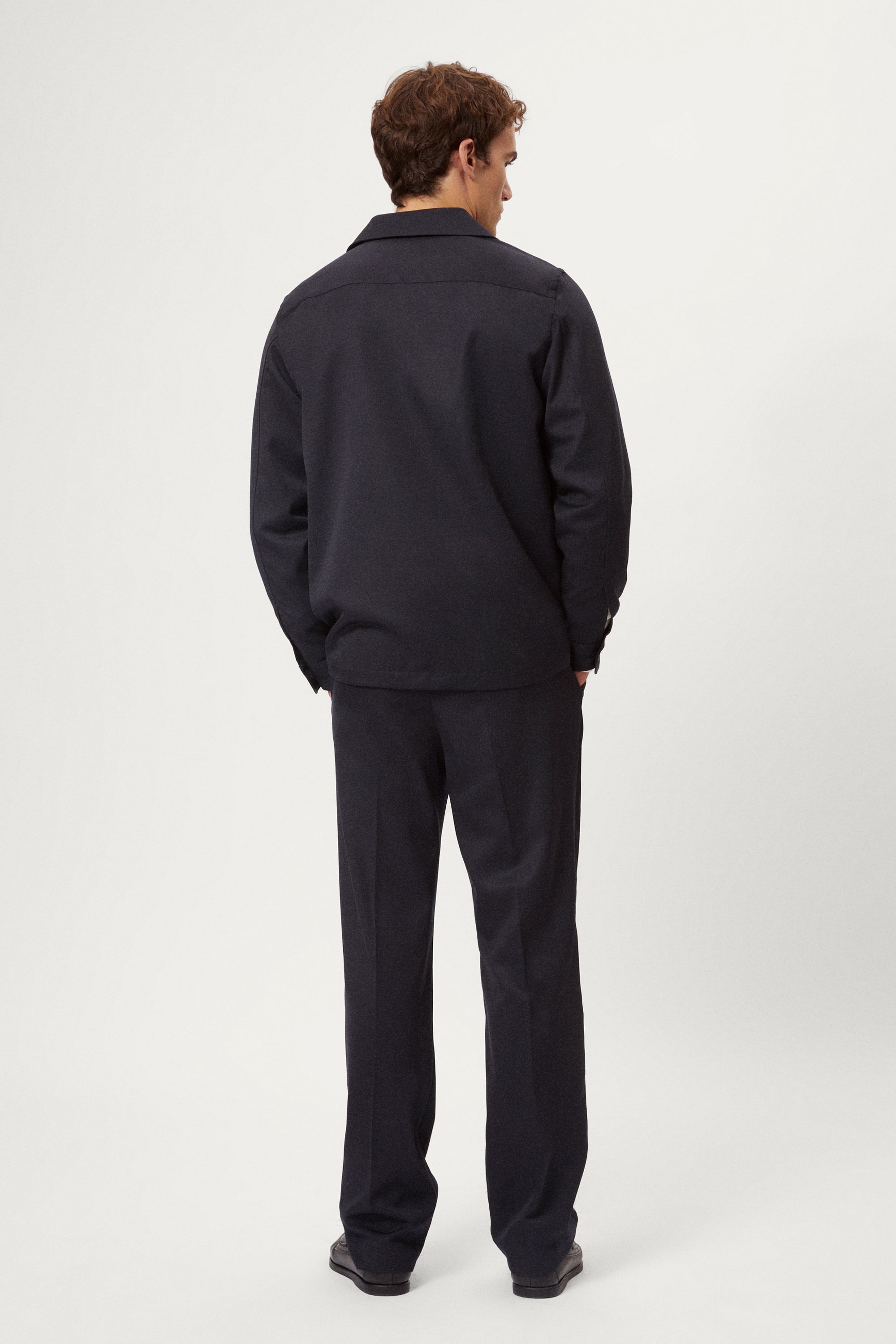 Man wearing a dark blue Twill Wool Overshirt over a white shirt on a light gray background