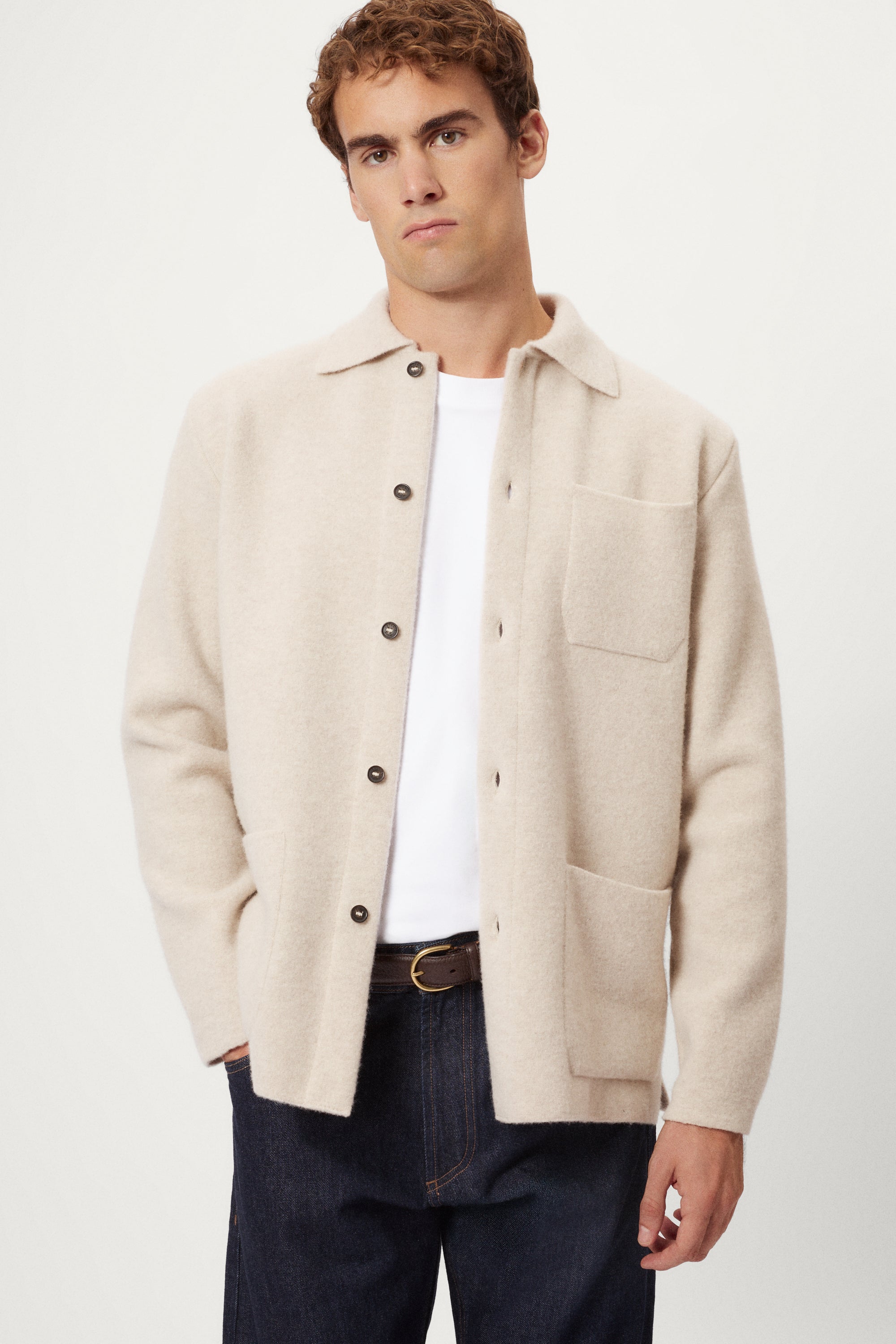 Person wearing a beige Boiled Wool Jacket over a knit sweater with a plain background