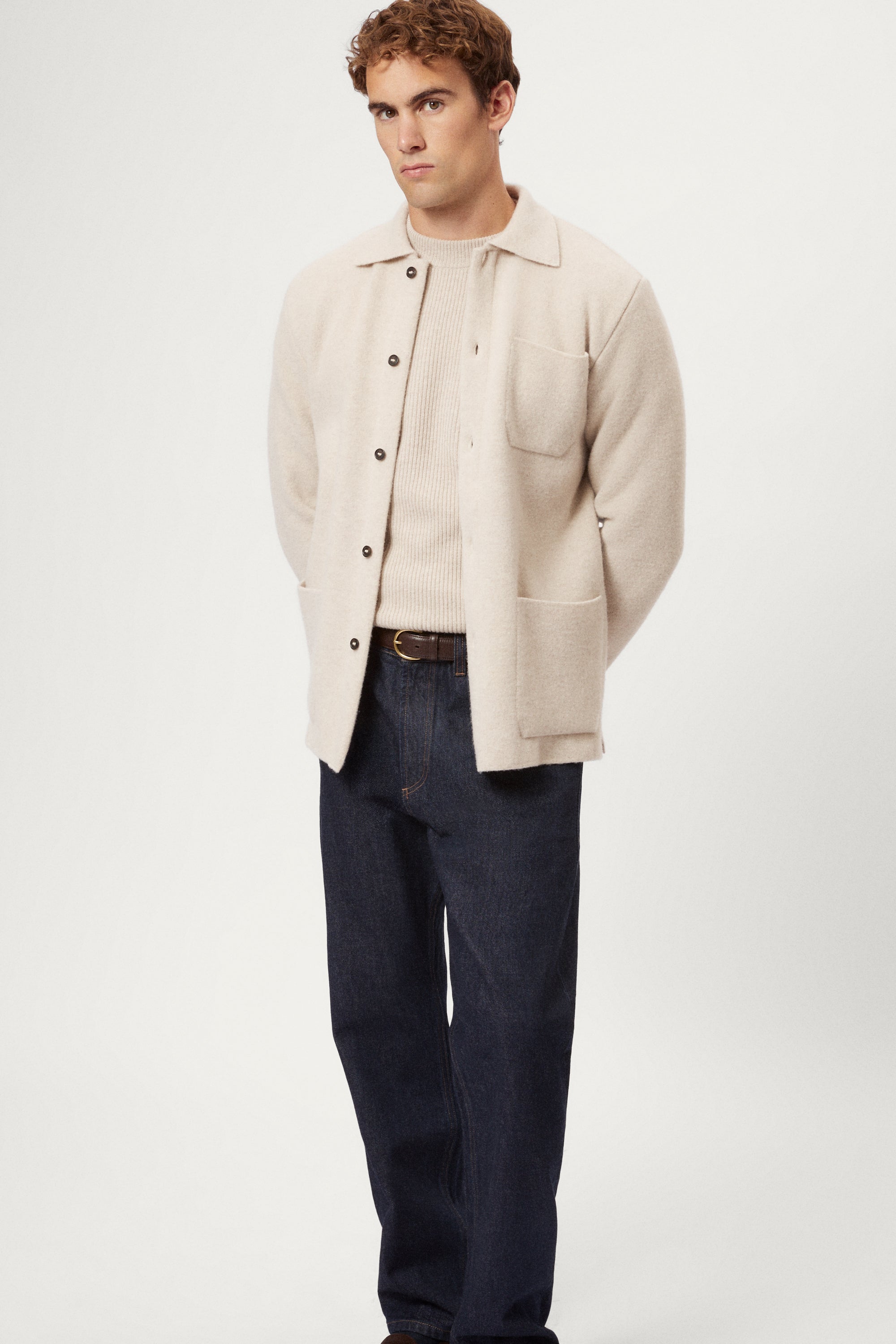 Person wearing a beige Boiled Wool Jacket over a knit sweater with a plain background