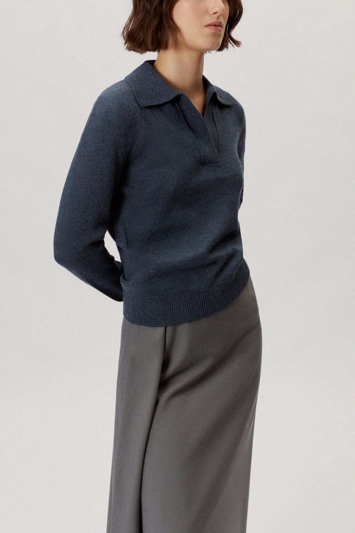 Person wearing a natural dye polo indigo blue on a light gray background