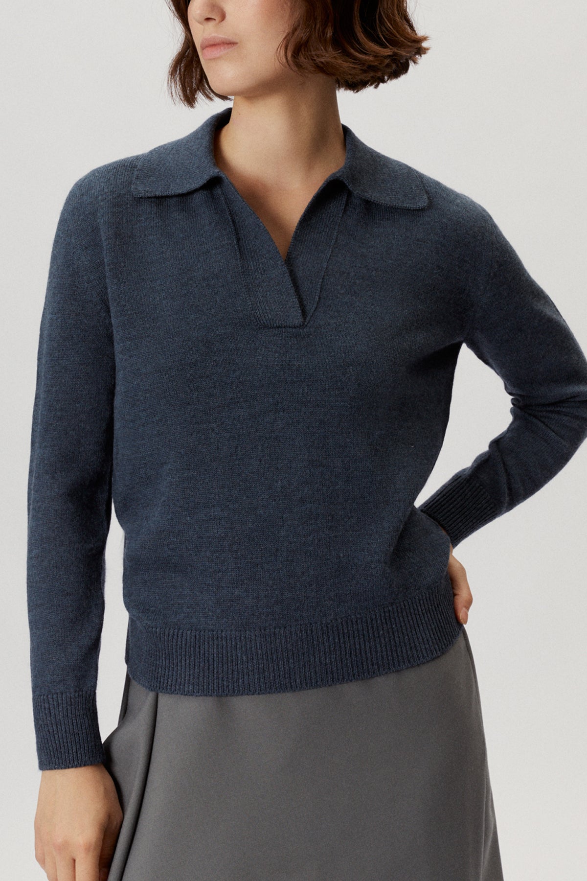 Person wearing a natural dye polo indigo blue on a light gray background