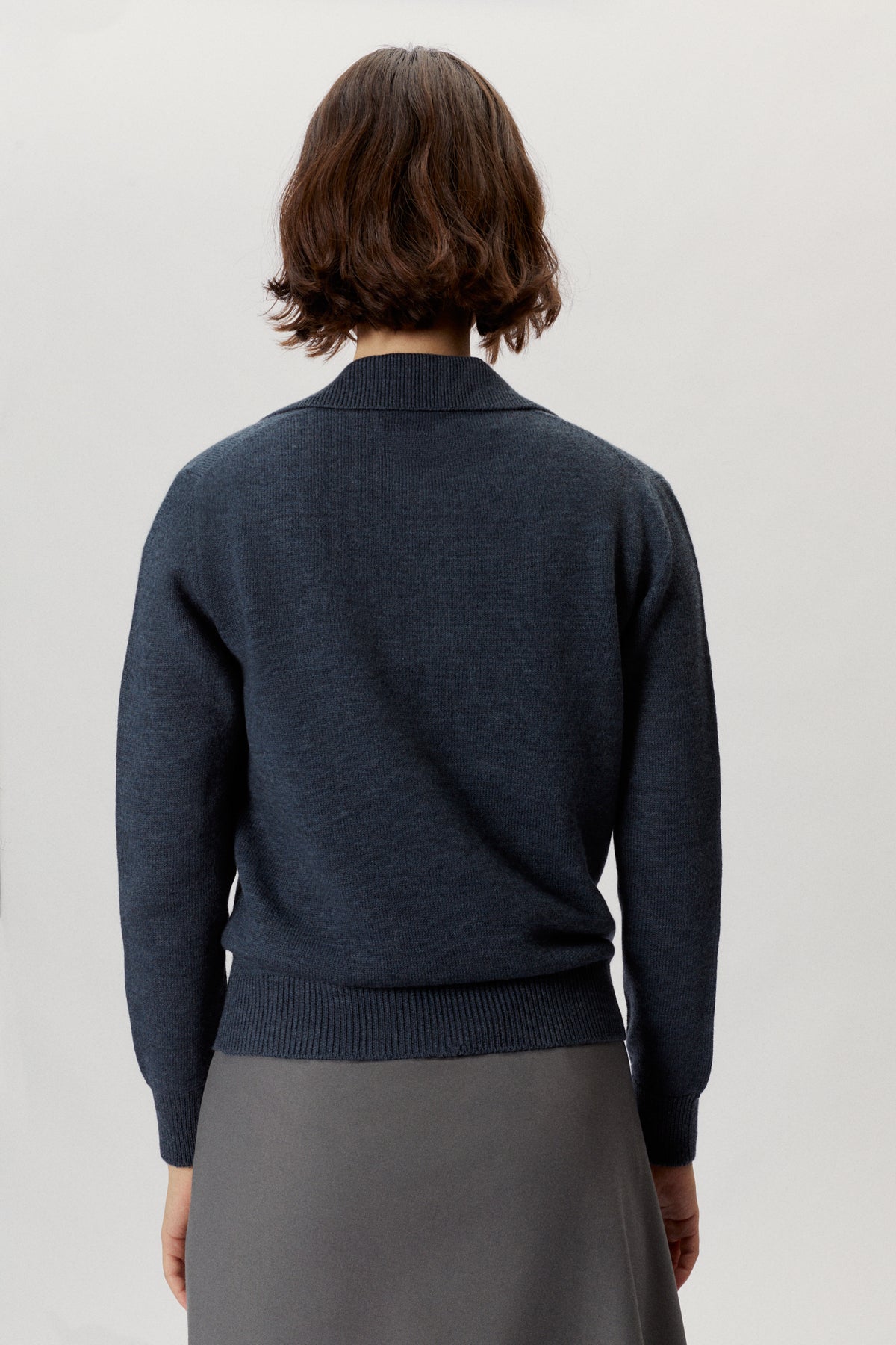 Person wearing a natural dye polo indigo blue on a light gray background