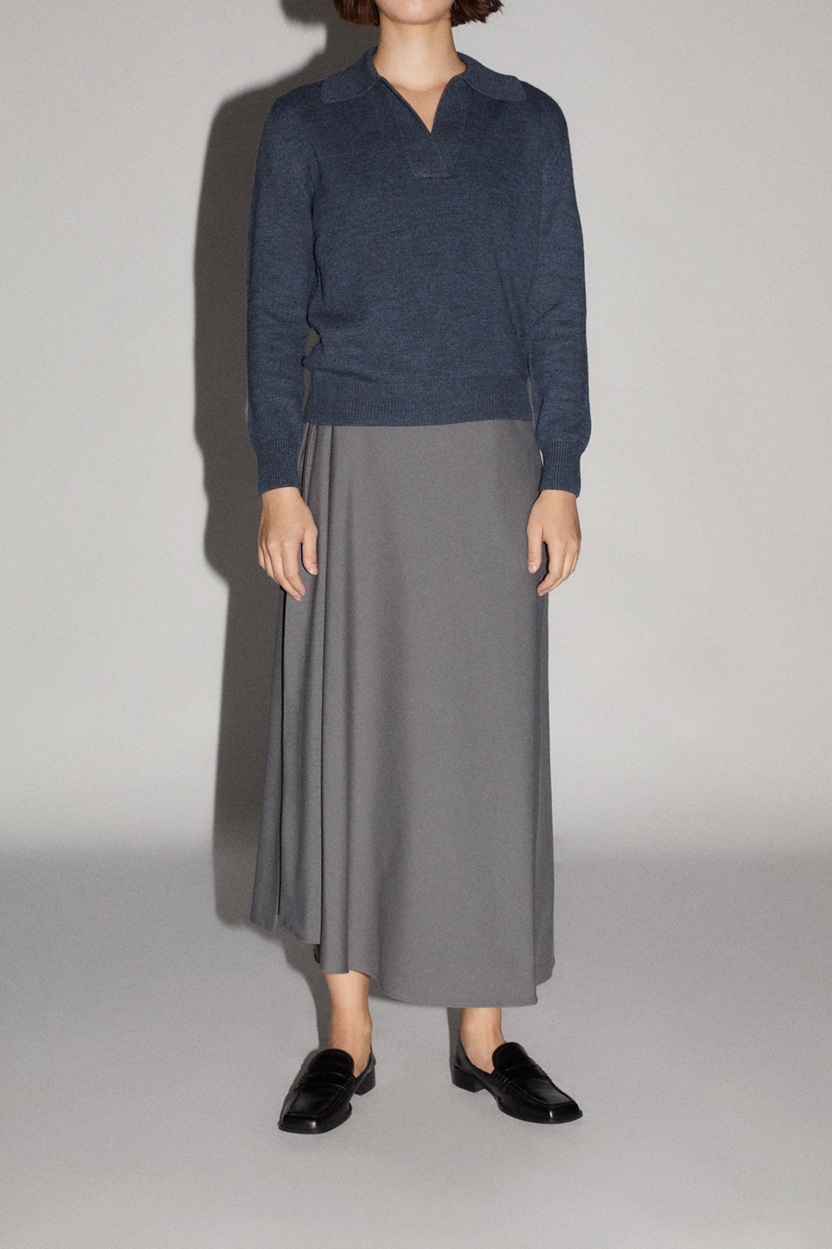 Person wearing a natural dye polo indigo blue on a light gray background