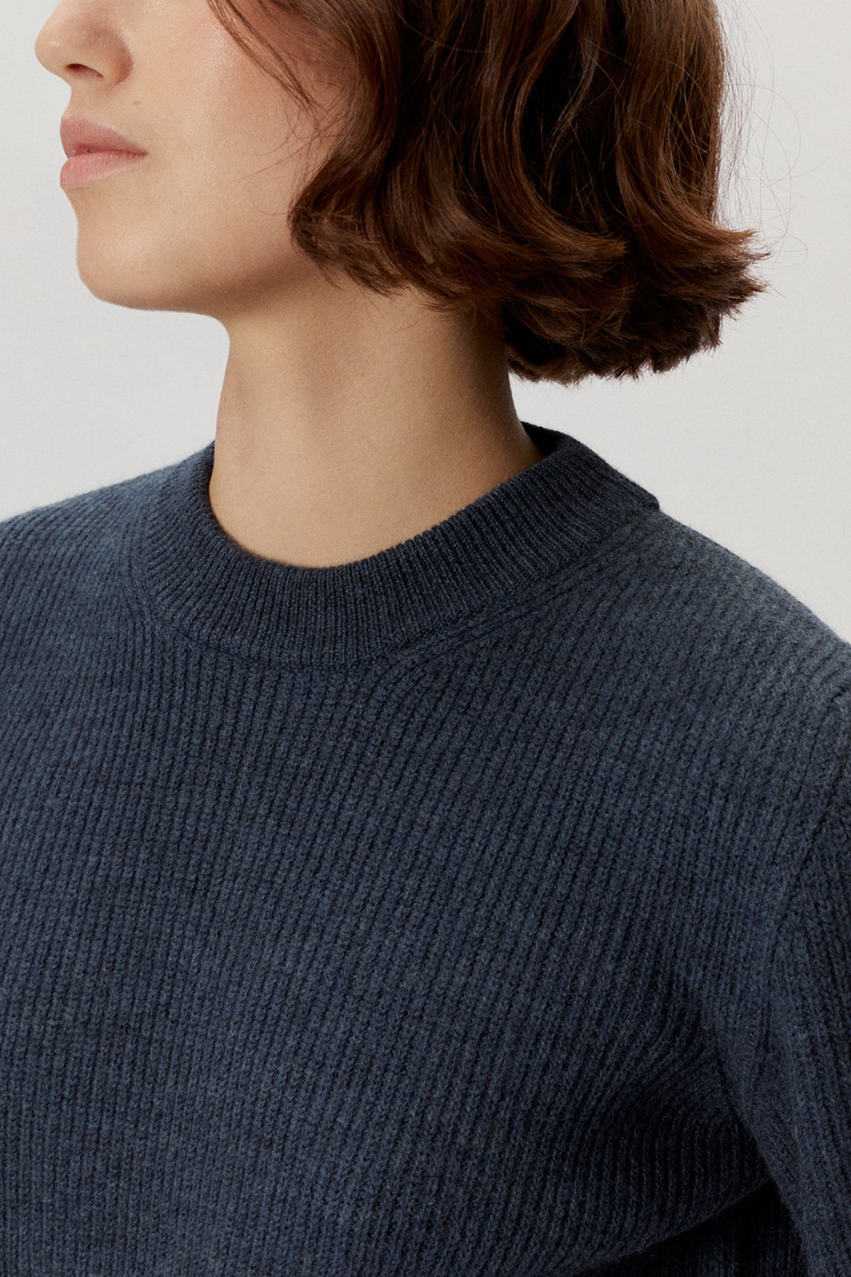 Person wearing a dark blue sweater with a neutral background