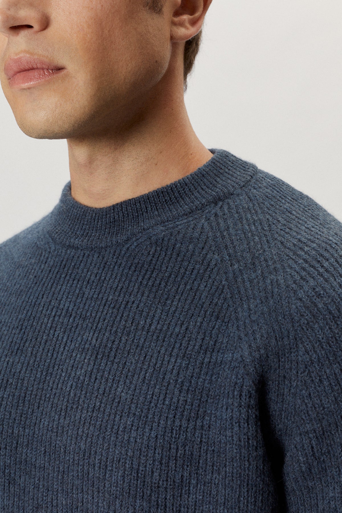 Close-up of a person wearing a blue knitted sweater against a light background