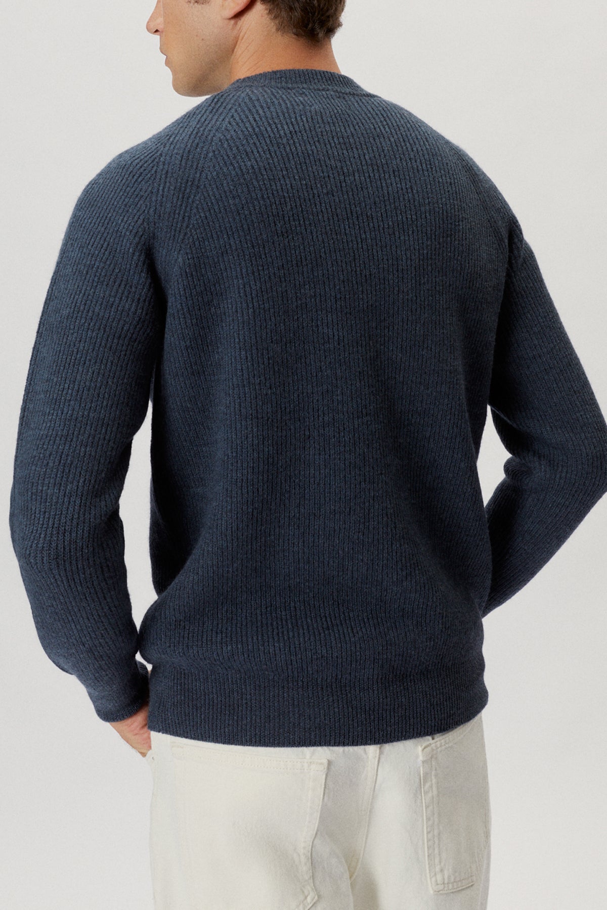 Man wearing a navy blue sweater on a light gray background
