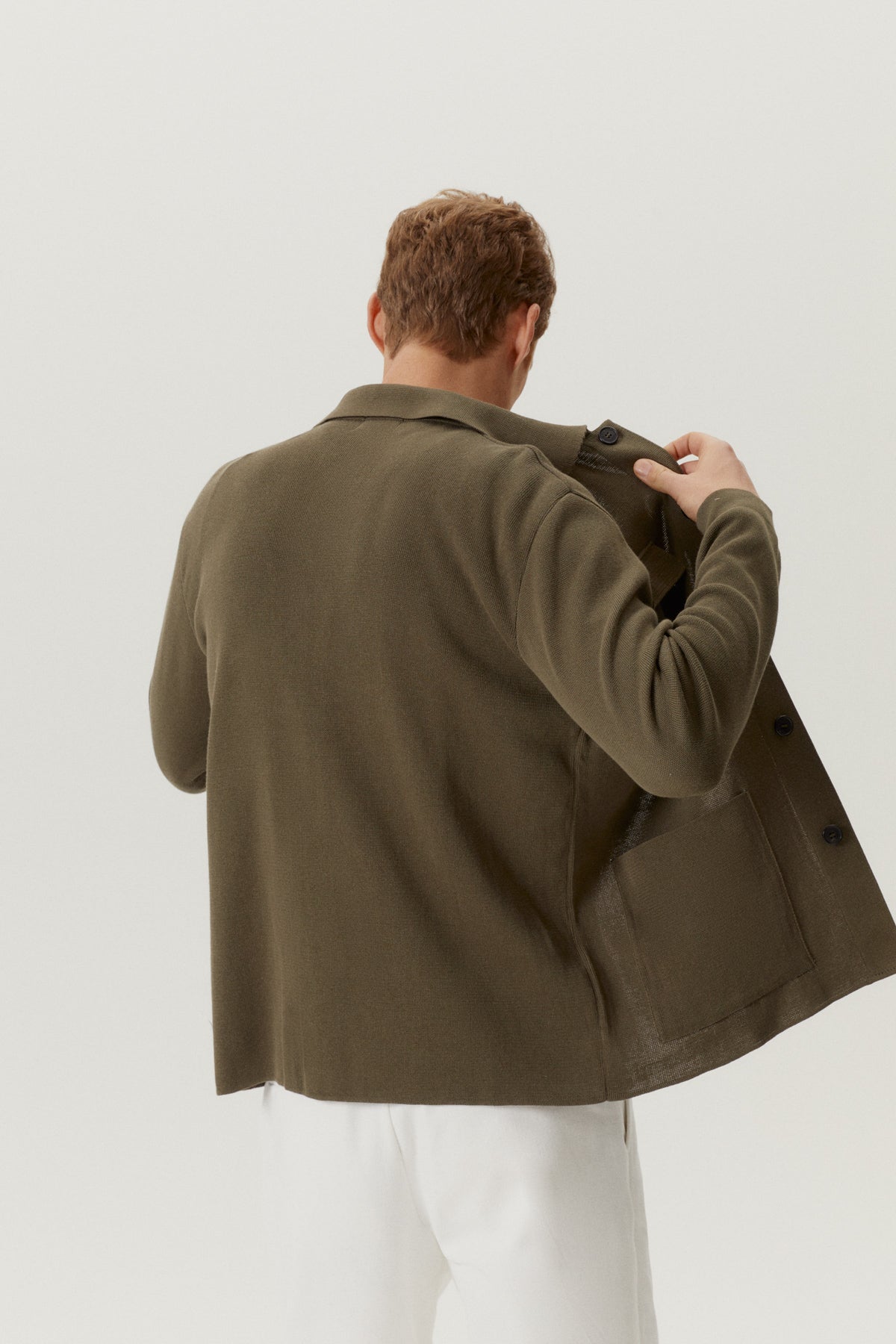 Person wearing a green jacket against a white background