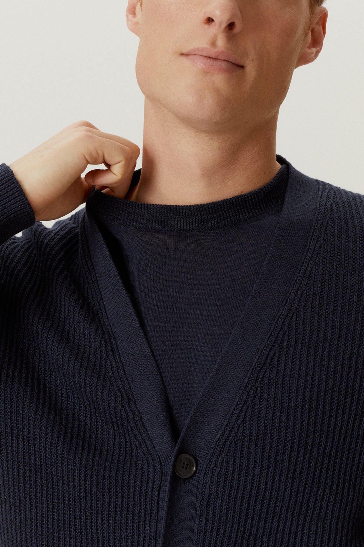 Man wearing a linen blue cardigan against a neutral background