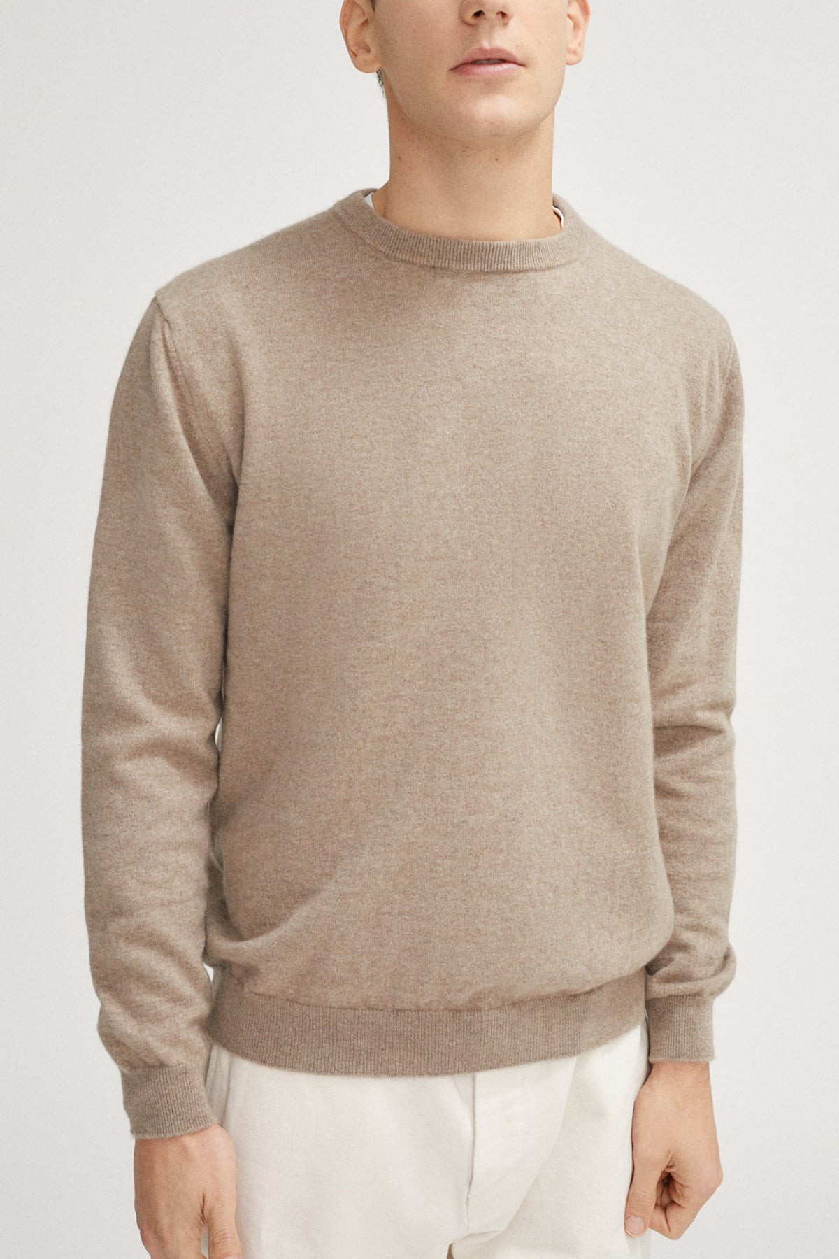 Man wearing a beige sweater on a light gray background