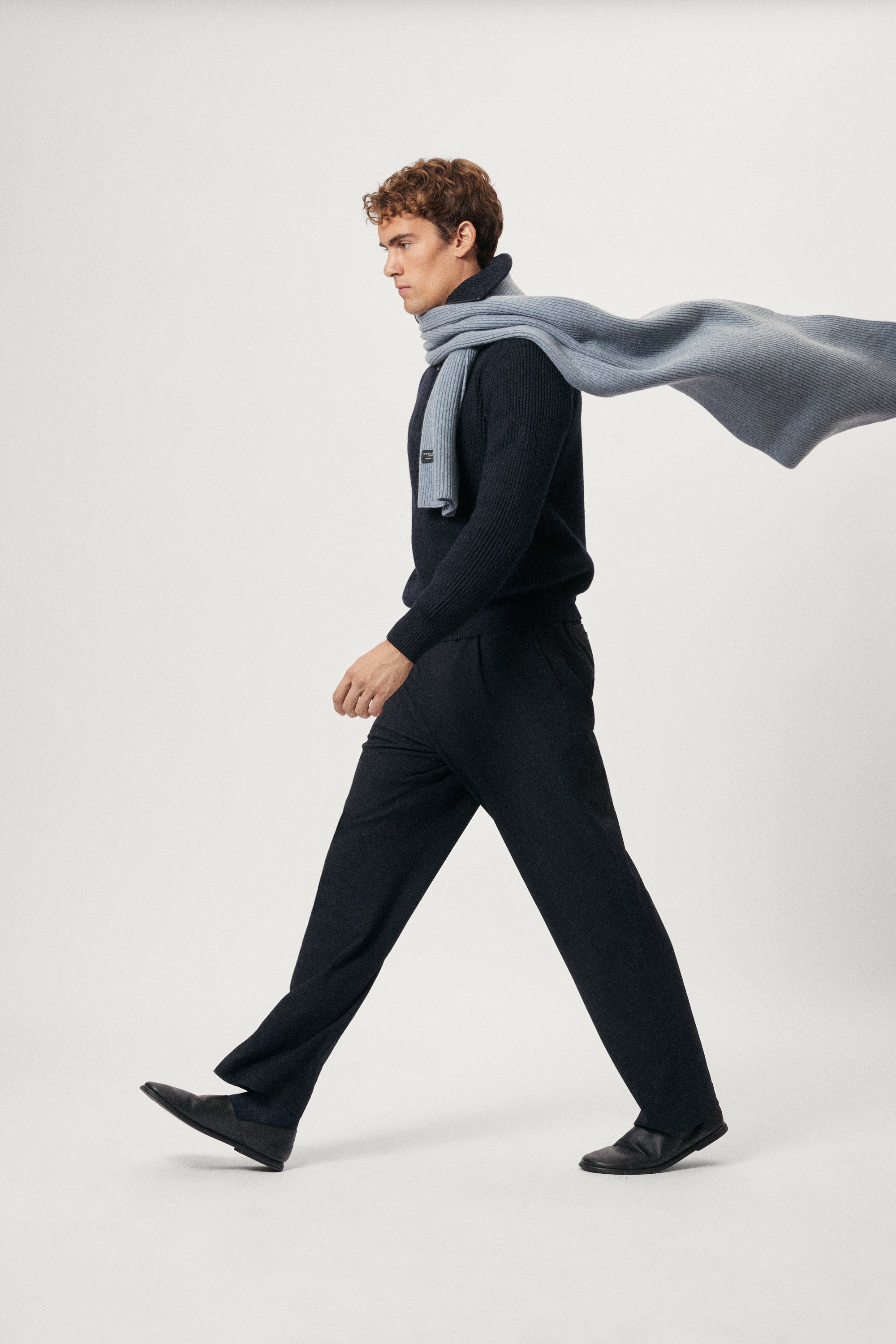 Man wearing a ash blue woolen scarf over his shoulders against a plain background