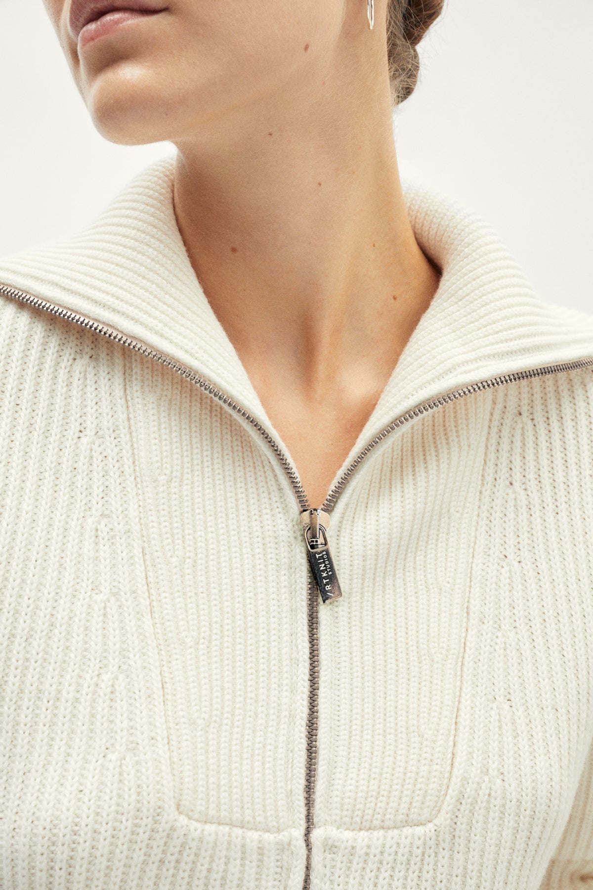 White ribbed sweater with a zipper on a light gray background