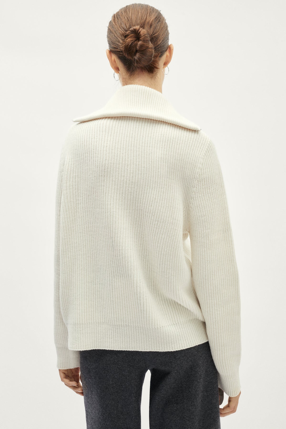 Person wearing a cream ribbed sweater on a white background