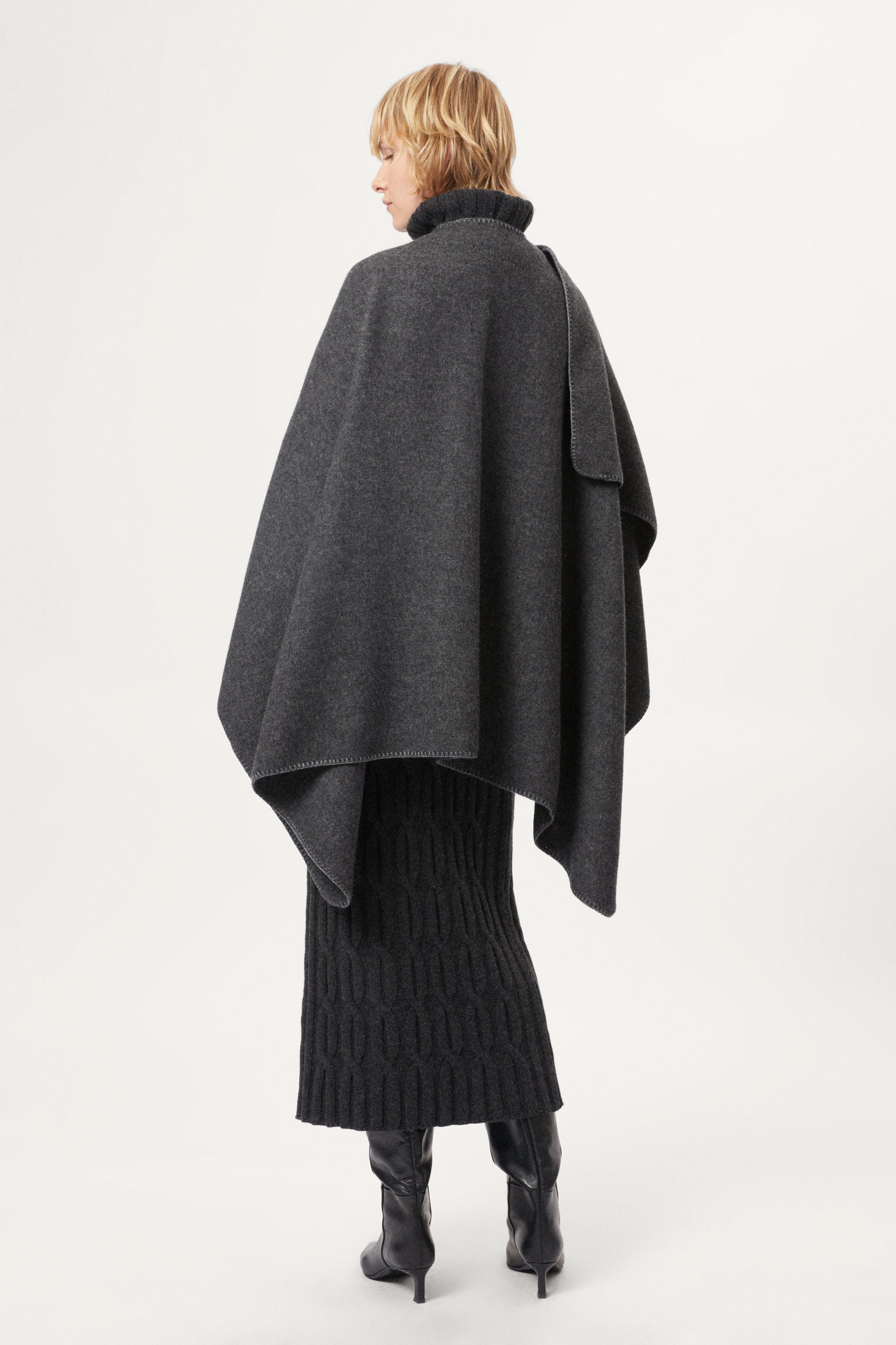 woman wearing a gray poncho over a grey outfit on a white background